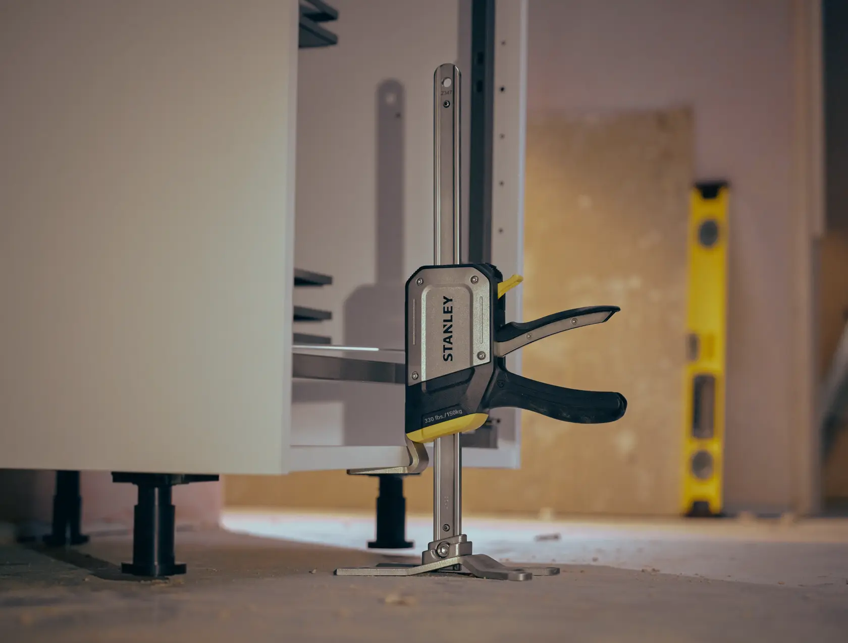 STANLEY FMHT83550-1 Zwinge befestigt Schrank, Fotografie aus seitlichem Winkel auf Werkstattboden.