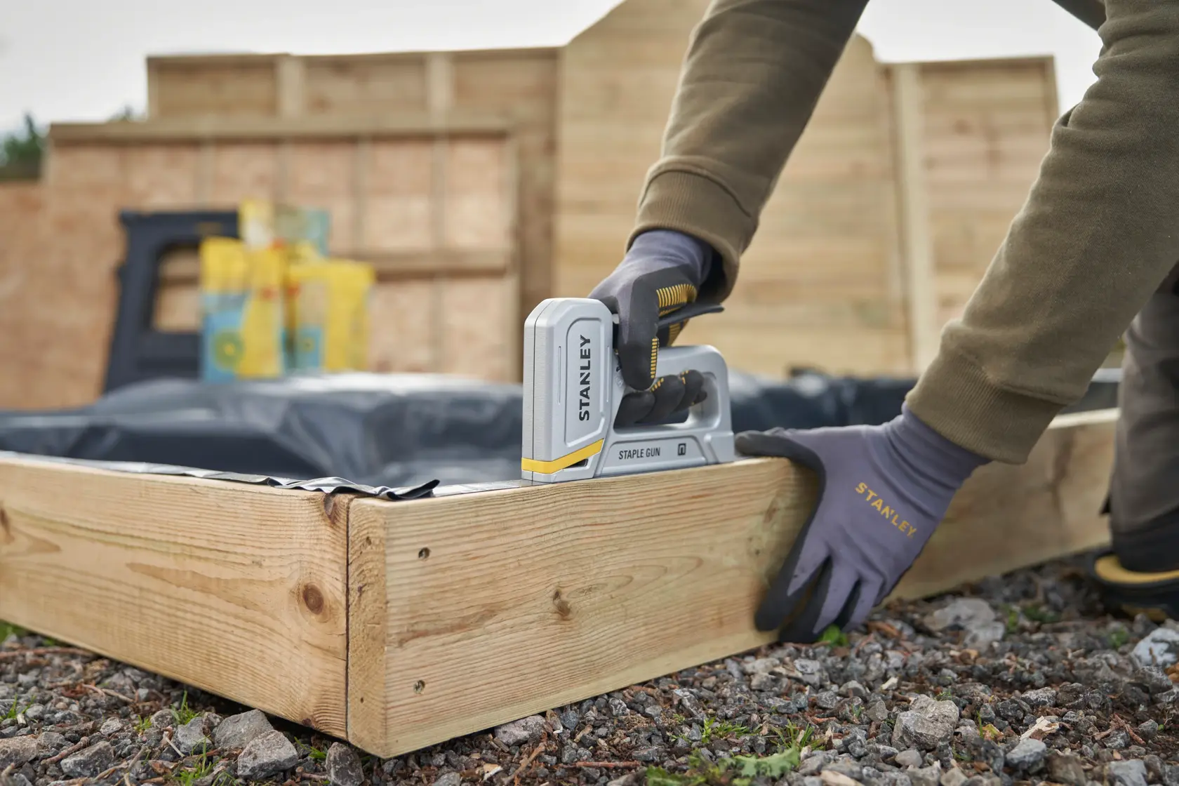 STANLEY STHT70150-0 Tacker bei der Befestigung von Kunststoff an einem Holzrahmen im Freien.