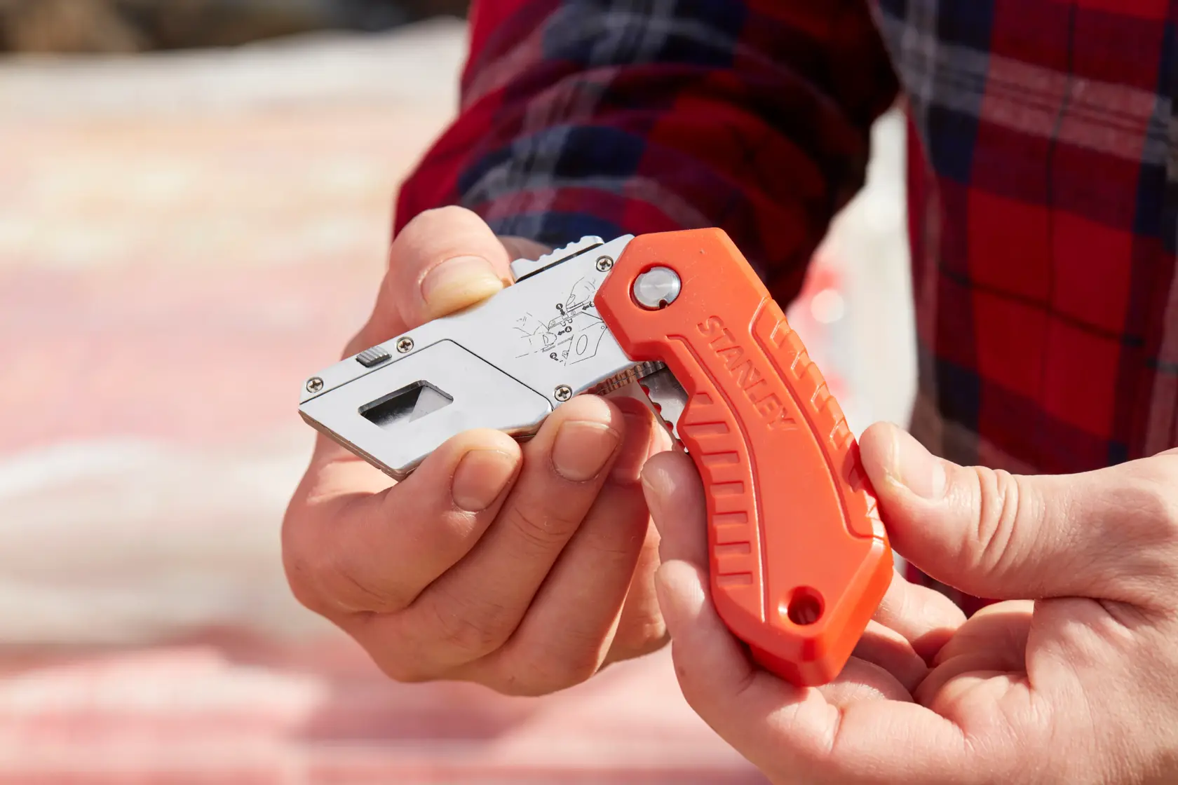 Stanley 0-10-243 Klappmesser mit orangefarbenem Griff, in der Hand im Freien gezeigt.