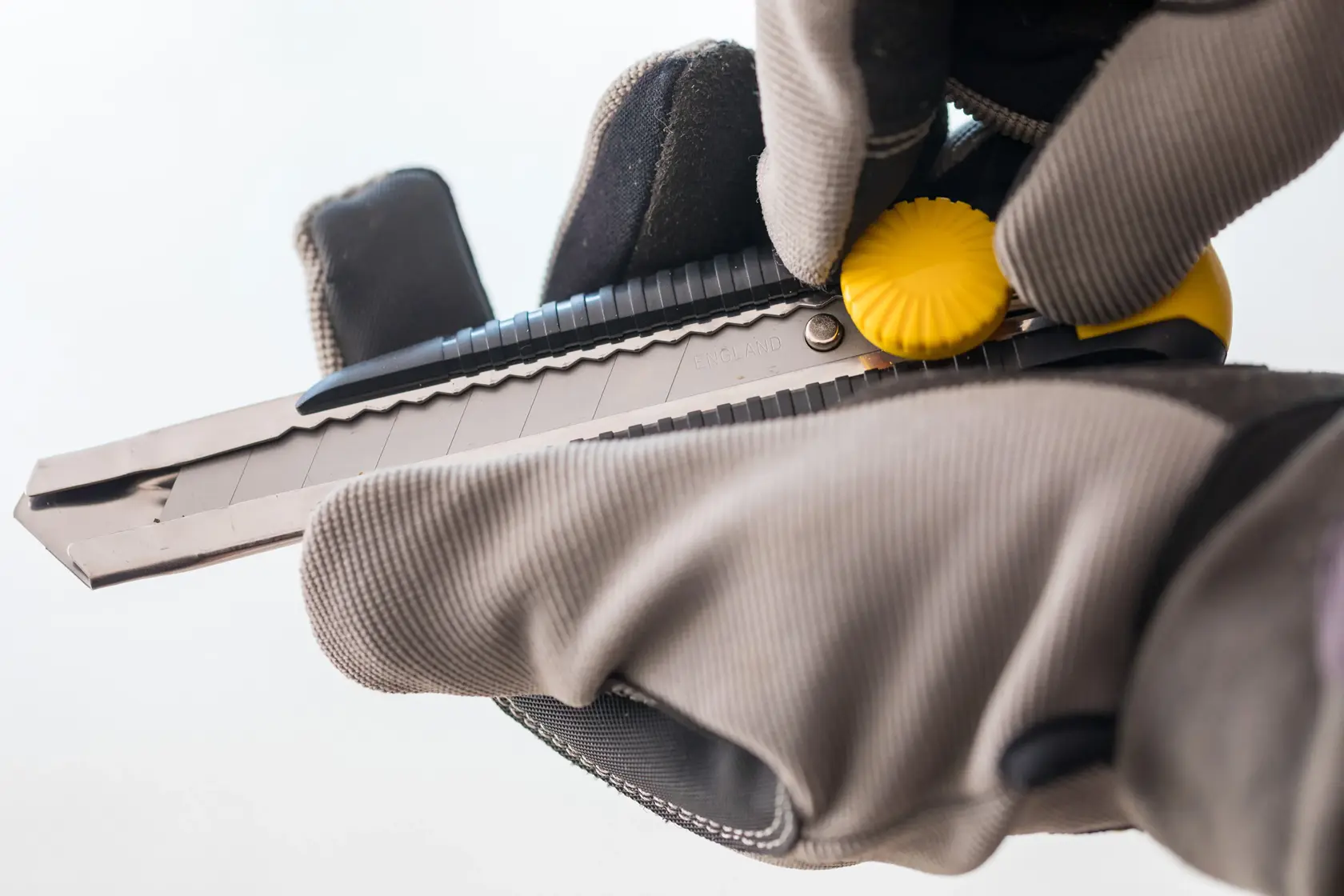 Foto vom STANLEY 0-10-418 Universalmesser mit Handschuhen, Nahaufnahme gelbes Drehrad und Klinge.