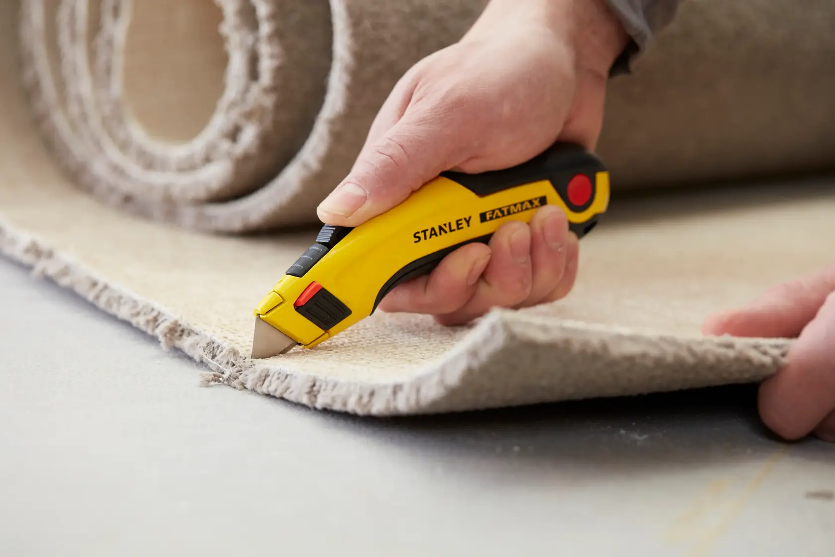 STANLEY 0-11-700 Universalmesser schneidet Teppich, Nahaufnahme, gelb-schwarzer Griff, FatMax-Serie.