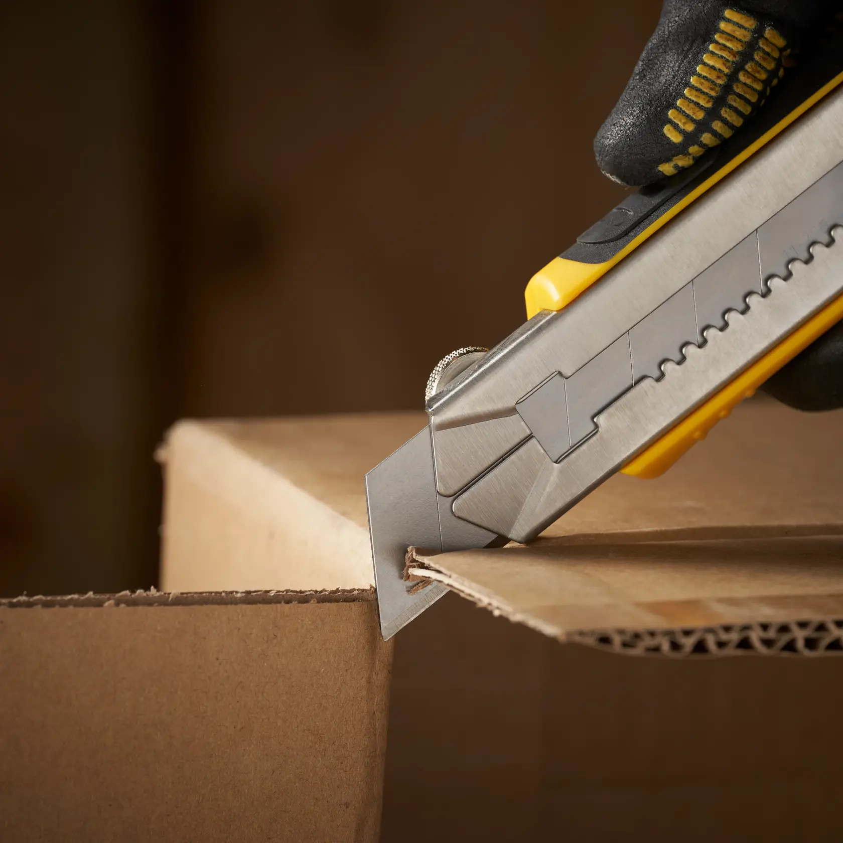 STANLEY 0-11-725 utility knife cutting cardboard box, close-up photo of product in use.
