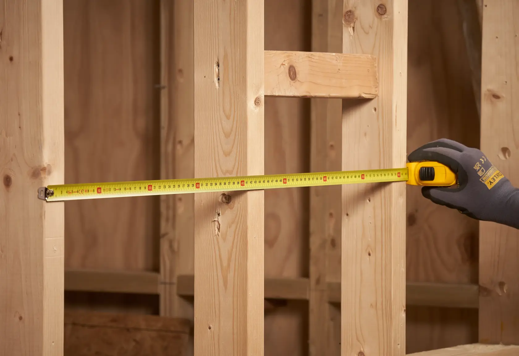 STANLEY 0-30-497 Maßband, das zwischen Holzständern gespannt ist, Nahaufnahme seitlich.