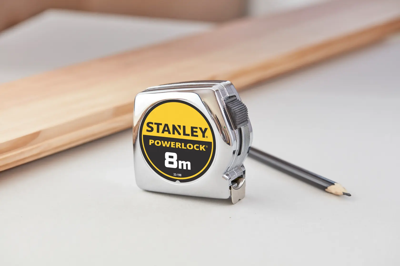 STANLEY 0-33-198 PowerLock 8m Maßband mit Chromgehäuse, auf Tisch mit Bleistift und Holzstück.
