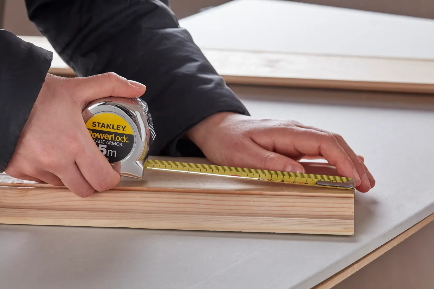 Photo of STANLEY 0-33-514 tape measure being used to measure a wooden board on a table.