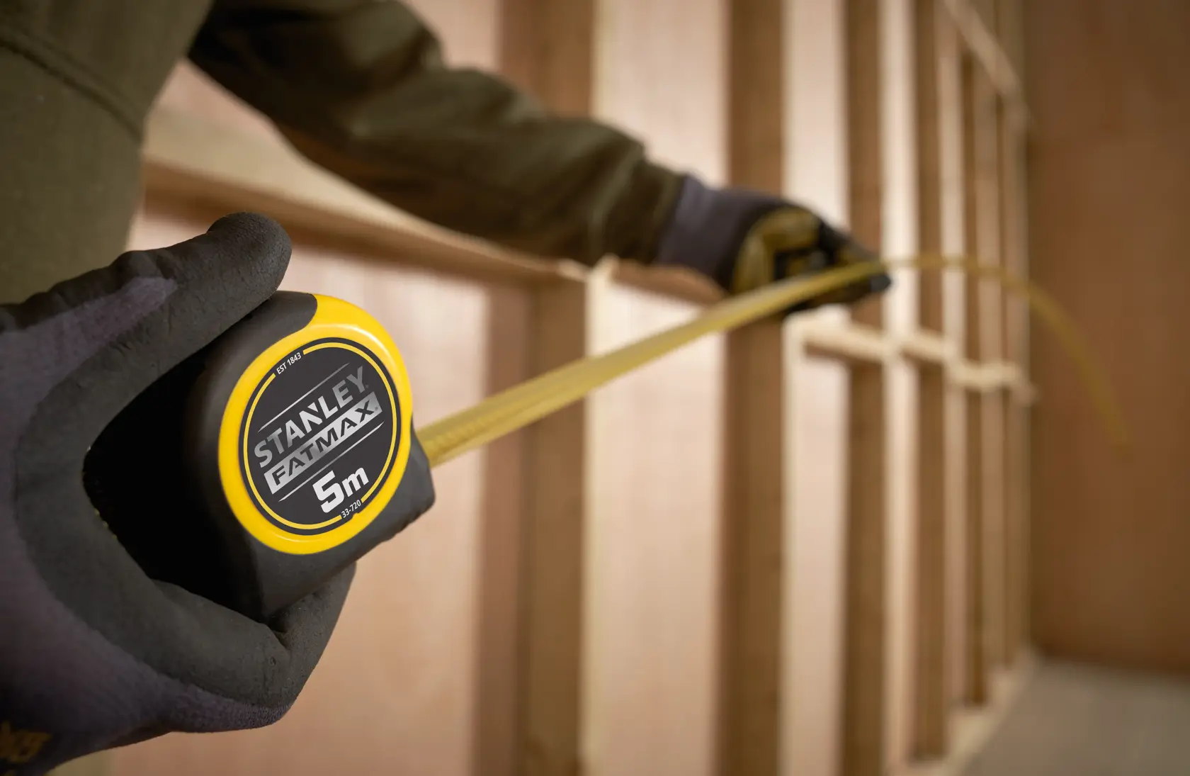 Photo of STANLEY 0-33-720 tape measure, yellow and black, being used to measure wood framing.