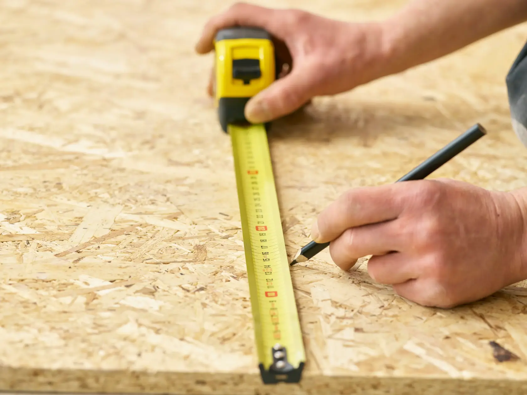 Photo of STANLEY 0-33-728 tape measure marking measurements on plywood, close-up angle.