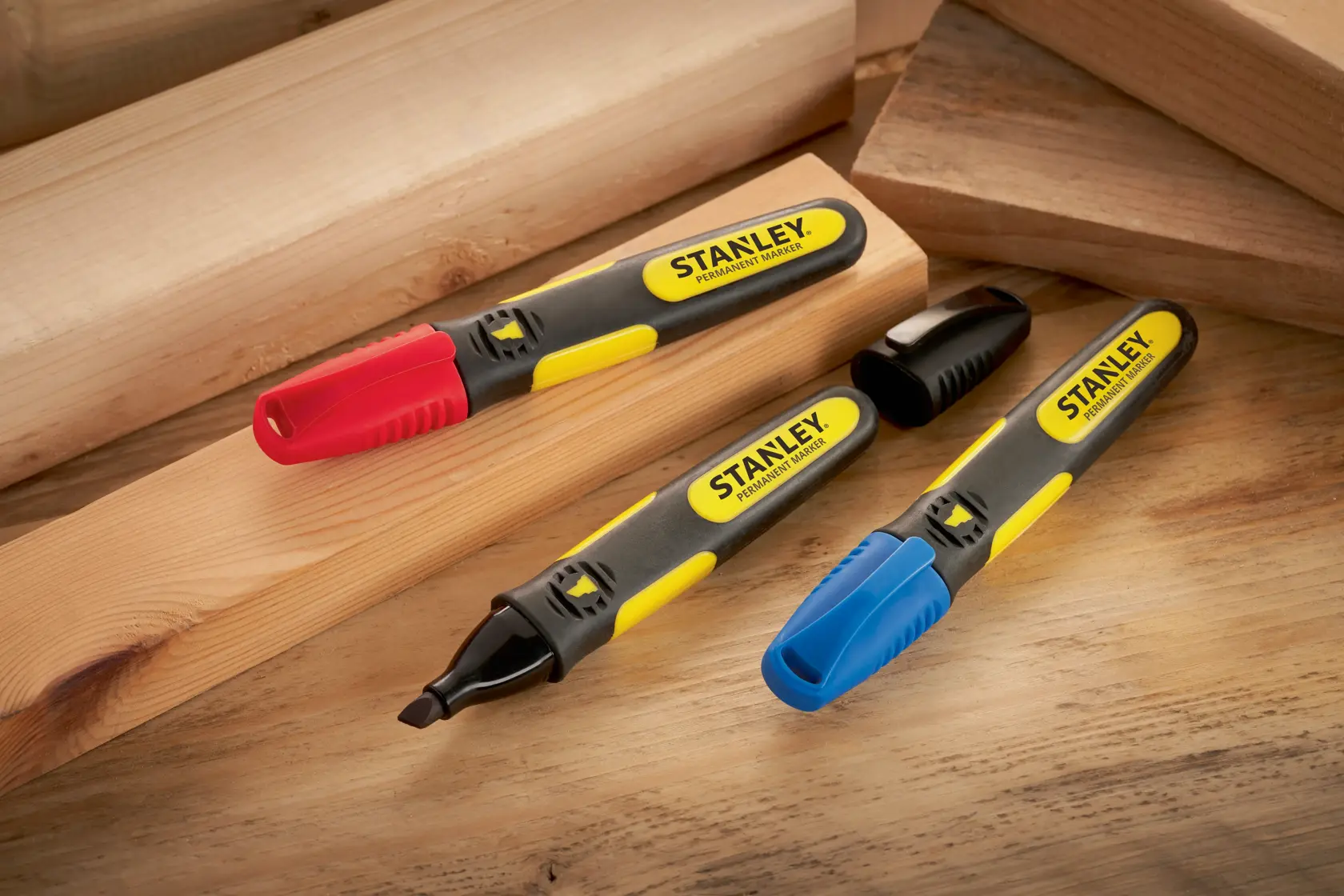 STANLEY SKU 0-47-315 Permanentmarker mit roten, blauen und schwarzen Kappen auf Holzplatten, schräge Ansicht.