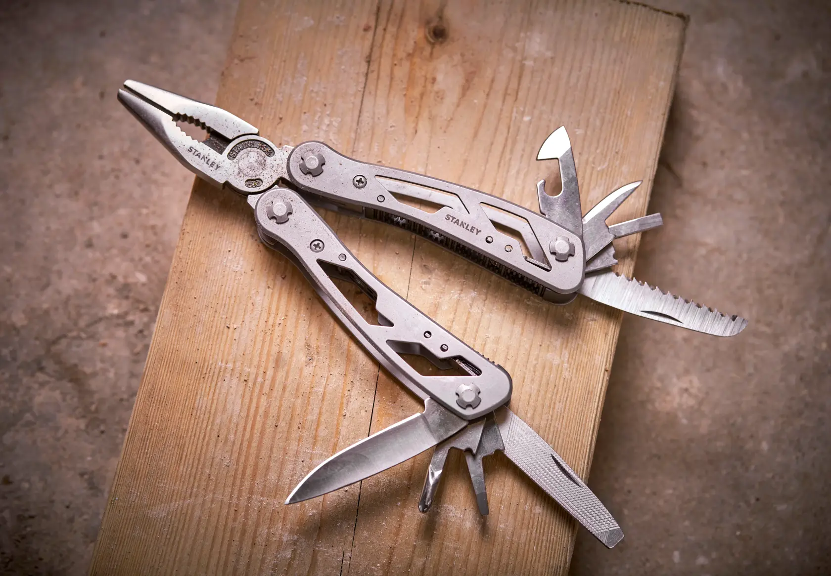 STANLEY 0-84-519 Multitool mit Zange und ausklappbaren Werkzeugen auf Holzoberfläche