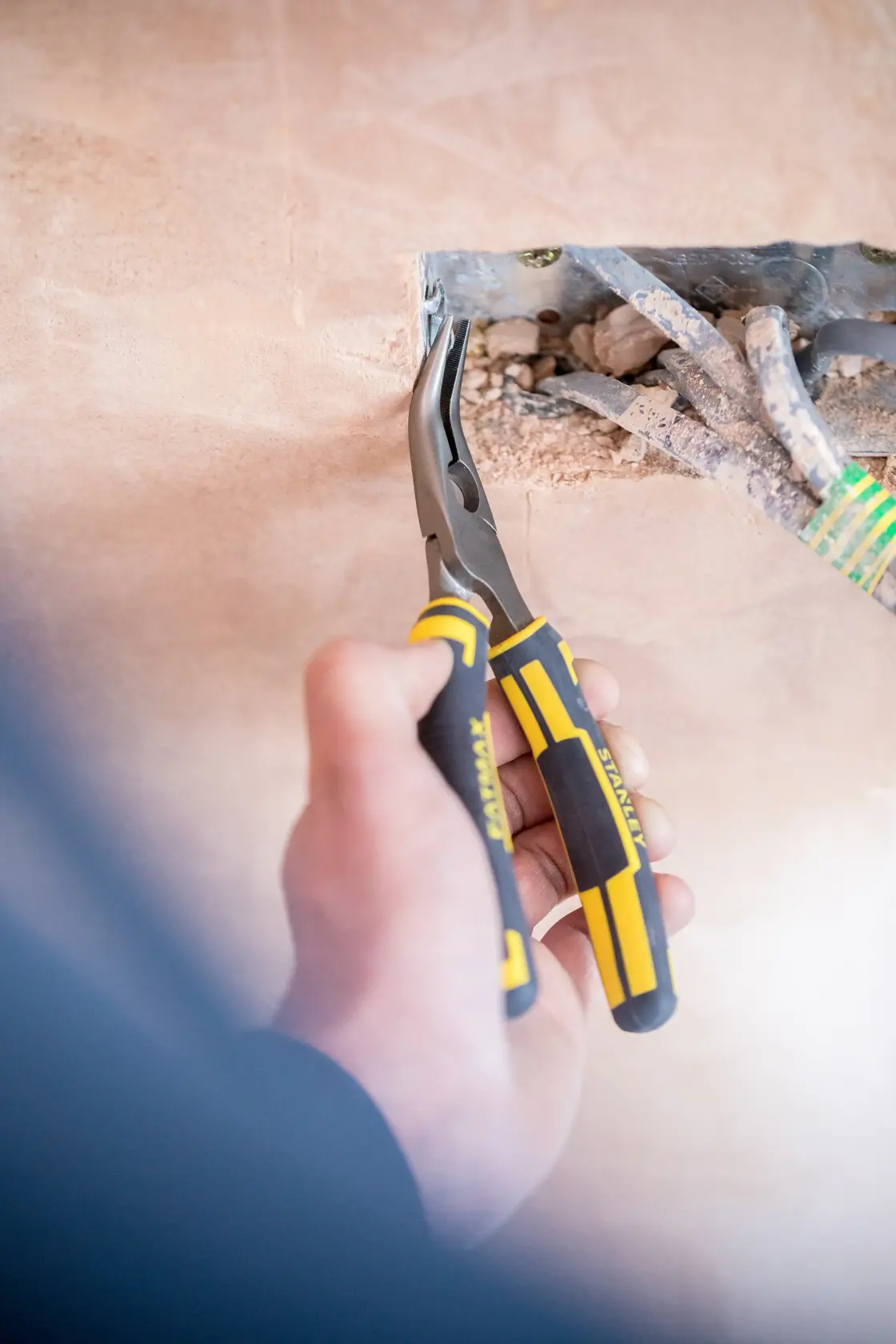 STANLEY 0-89-871 Spitzzange mit gelb-schwarzen Griffen im Einsatz bei Elektroinstallationen.