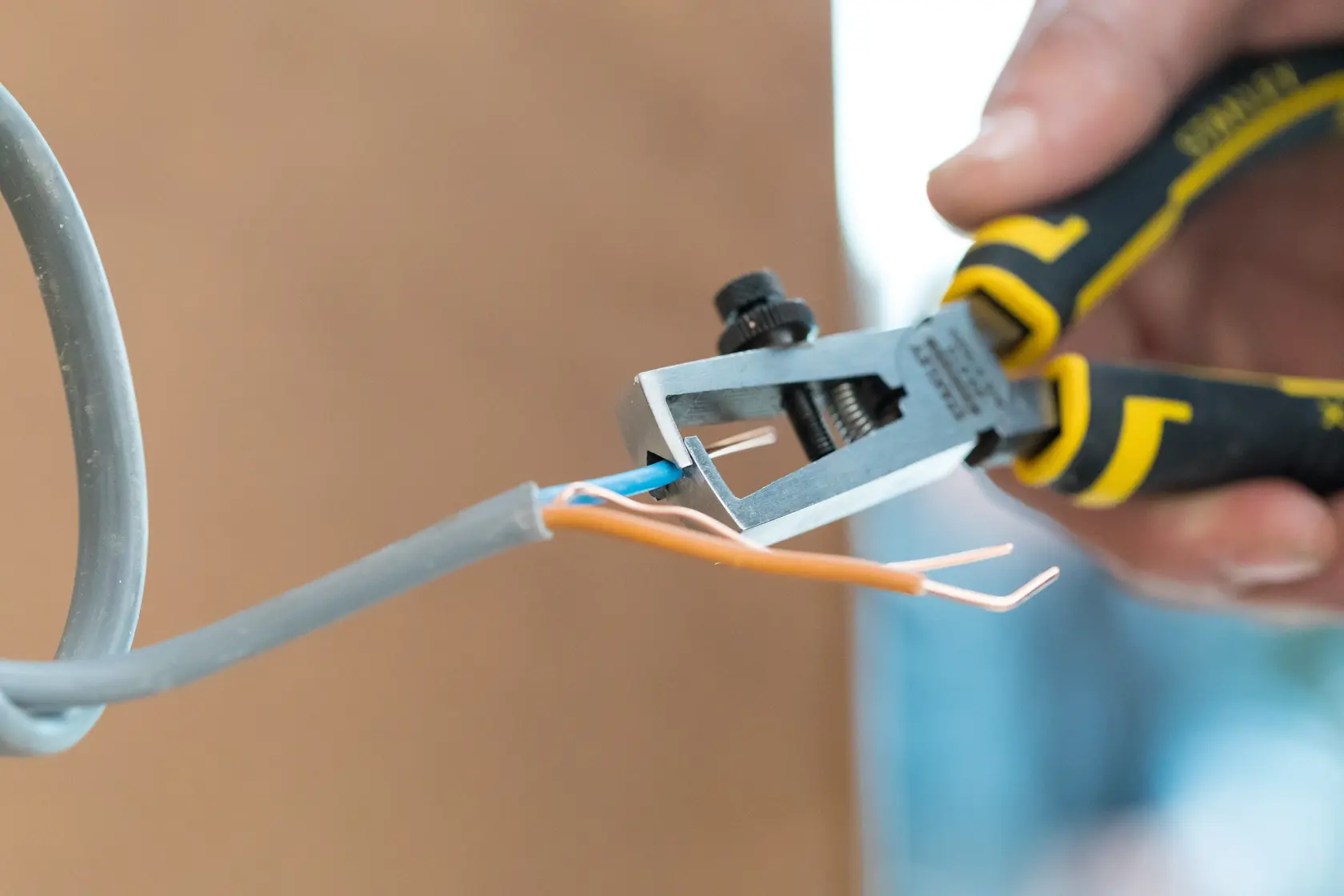 STANLEY 0-89-873 wire stripper cutting insulation from electrical cable, close-up view.
