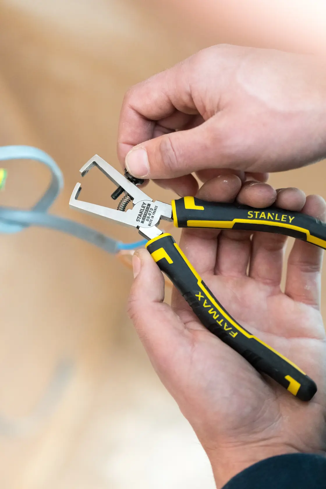 STANLEY 0-89-873 black and yellow pliers with FATMAX grip held in hand, close-up view.