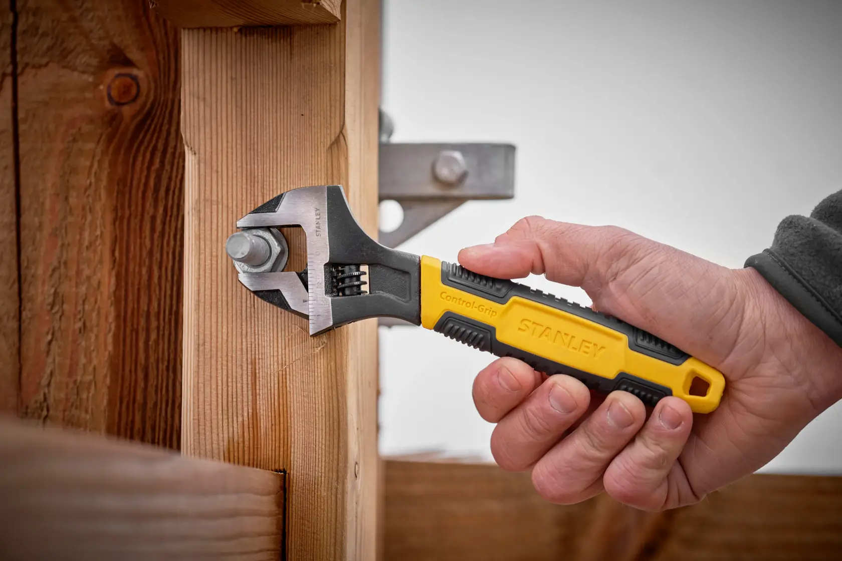 STANLEY 0-90-947 adjustable wrench with yellow and black Control-Grip handle in use tightening a bolt.