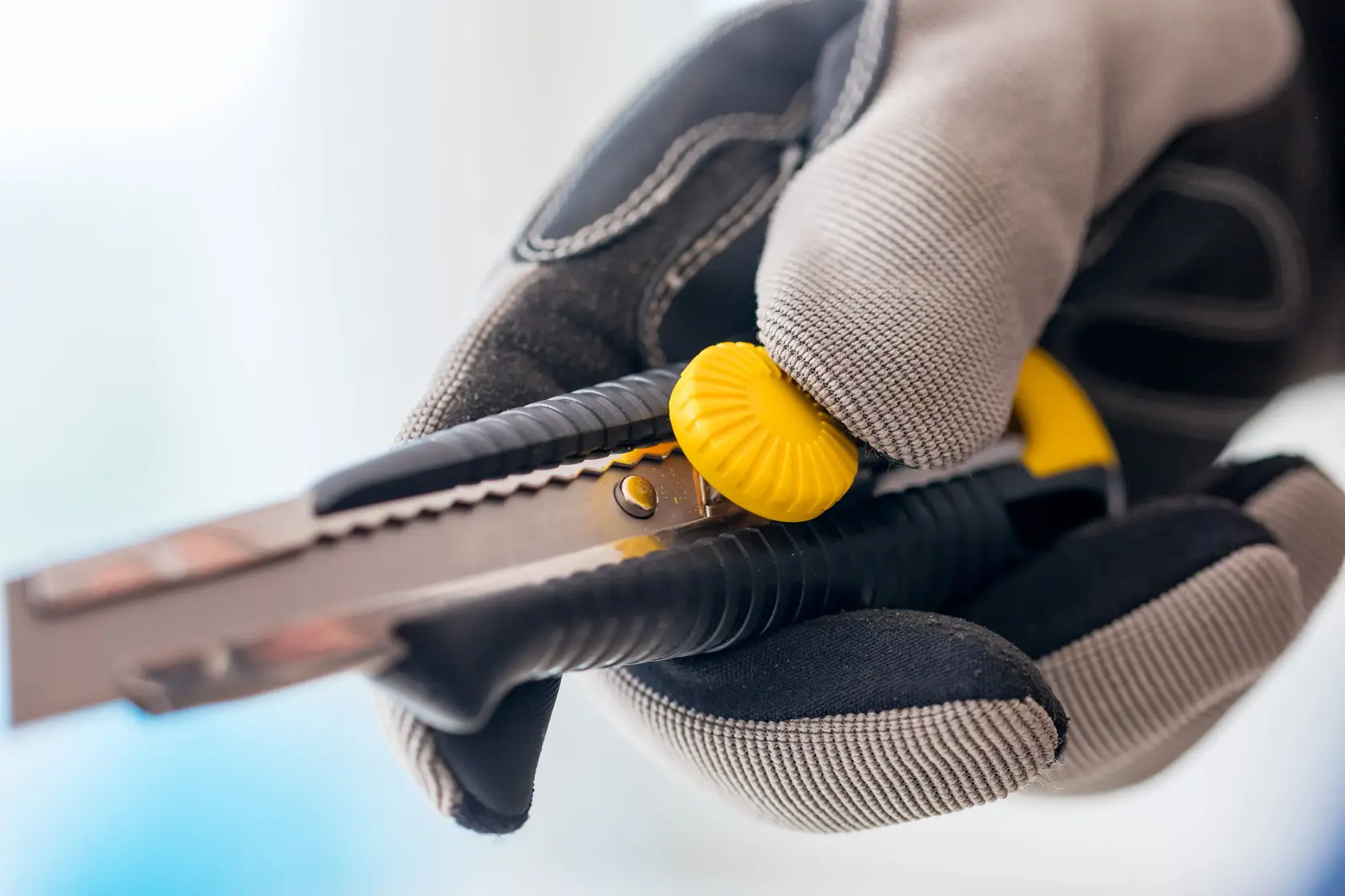 STANLEY 1-10-418 utility knife with yellow knob held in gloved hand, close-up photo.