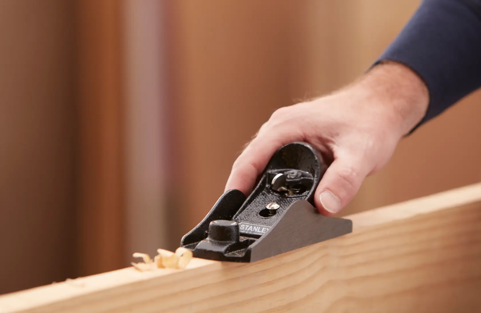 STANLEY 1-12-220 Blockhobel glättet eine Holzkante, Nahaufnahme mit Hand am Werkzeug.