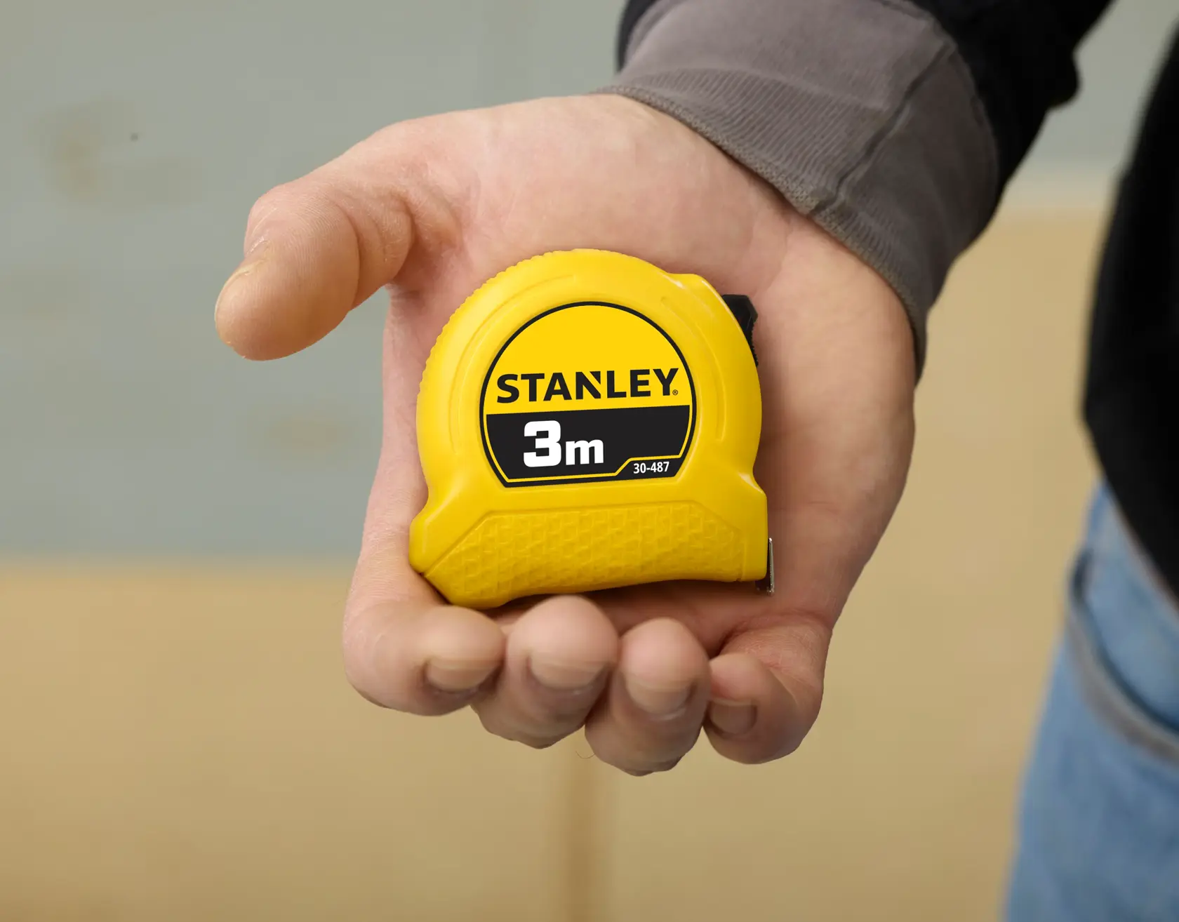 Foto vom STANLEY 1-30-487 gelben 3m Maßband in der Hand, kompaktes Kunststoffdesign.