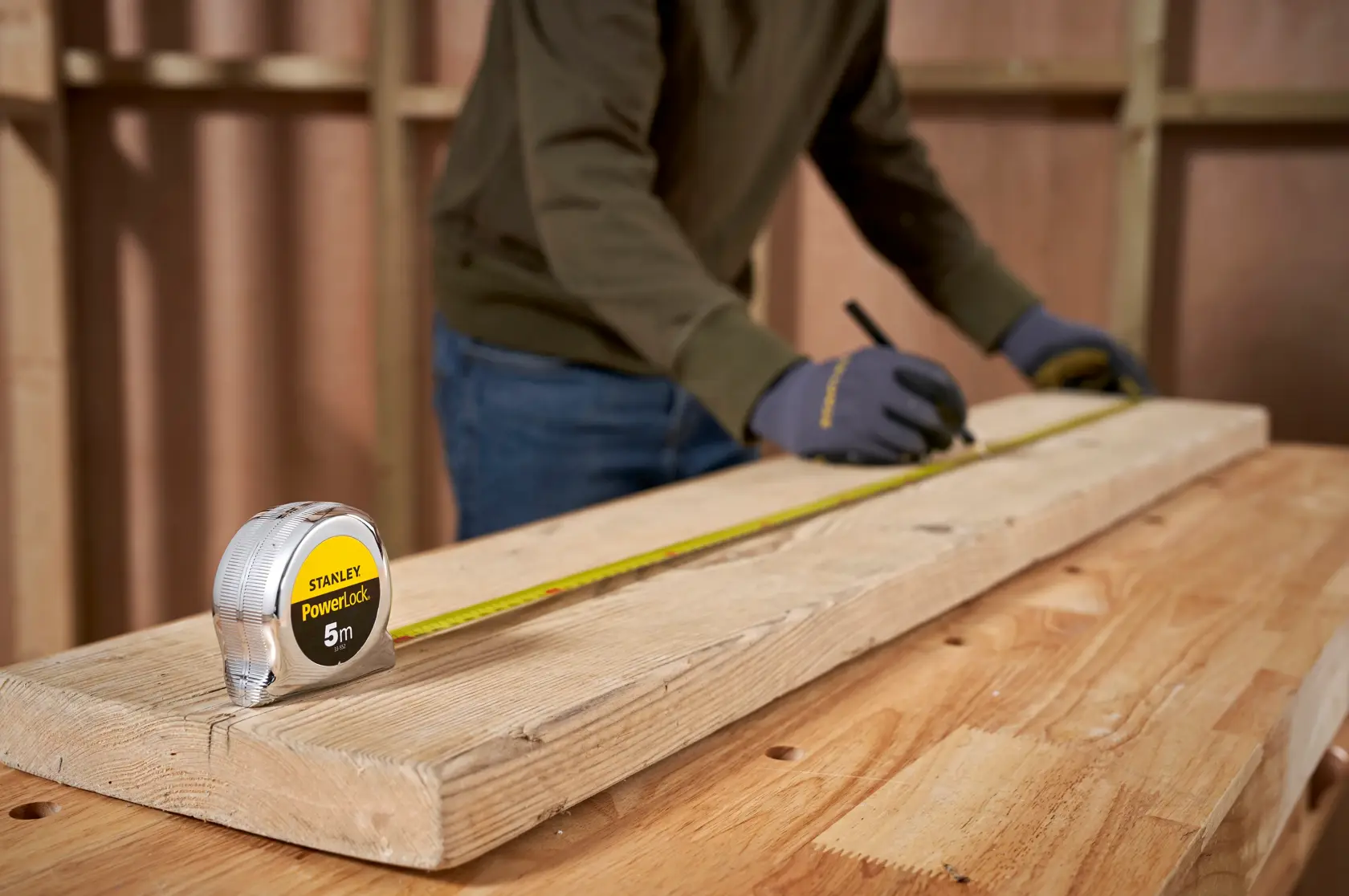 STANLEY 1-33-552 tape measure on wood, worker marks board during carpentry, product photography.