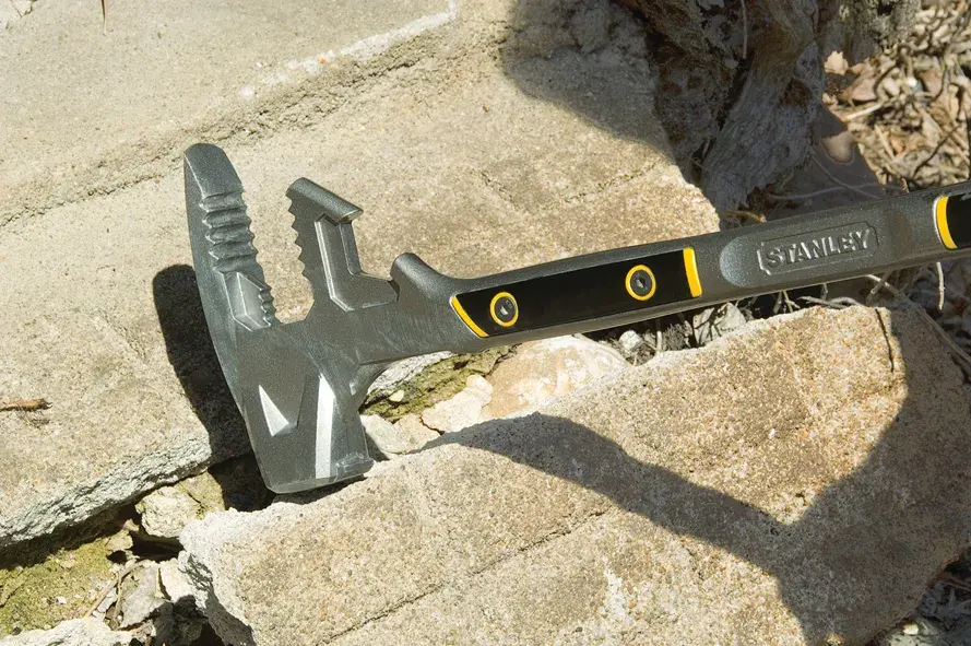 STANLEY 1-55-120 demolition hammer with black and yellow handle on stone rubble outdoors.