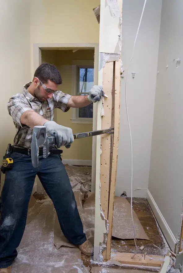 Photo of person using STANLEY 1-55-120 wrecking bar during interior wall demolition, tool belt visible.