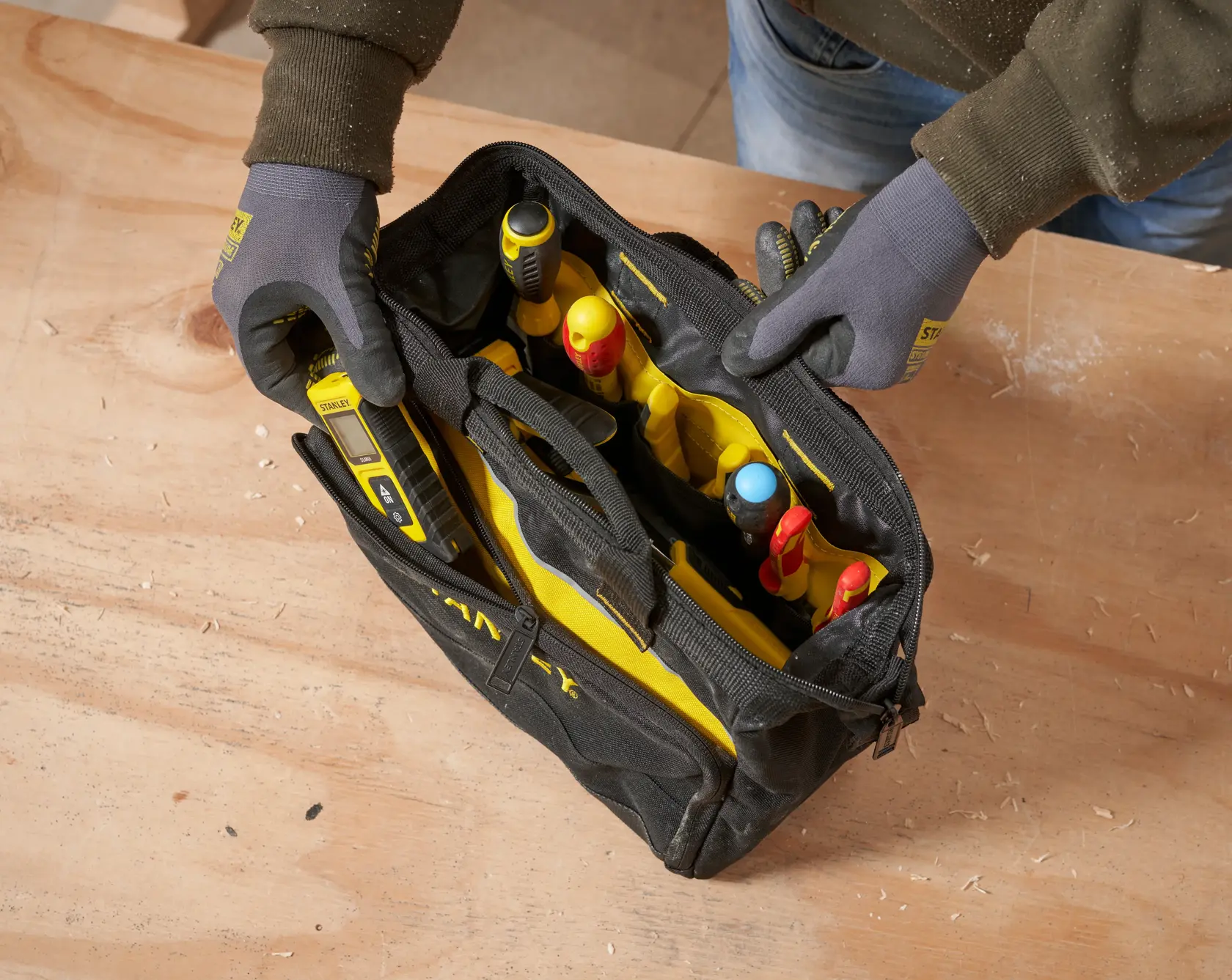 STANLEY 1-93-330 Werkzeugtasche mit verschiedenen Handwerkzeugen, Draufsicht, auf Holzoberfläche.