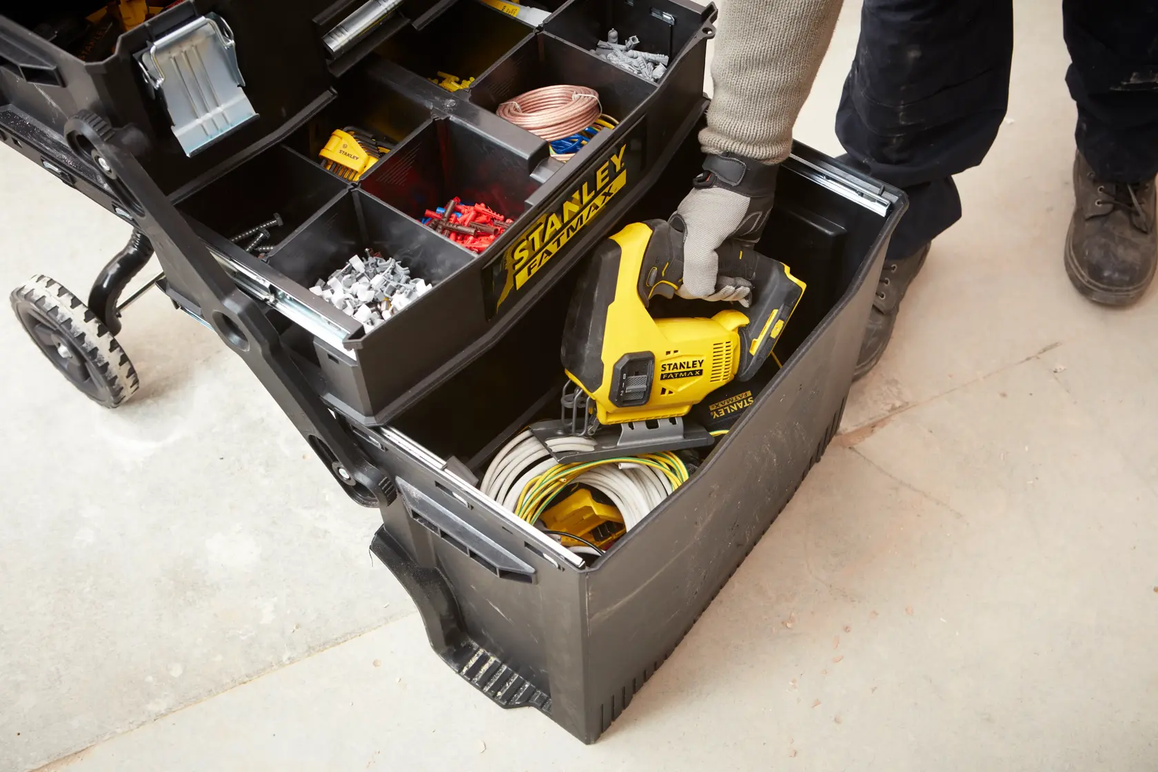 STANLEY 1-94-210 Werkzeugorganizer mit Fächern, Arbeiter greift auf unteres Fach mit Elektrowerkzeug und Kabeln zu.