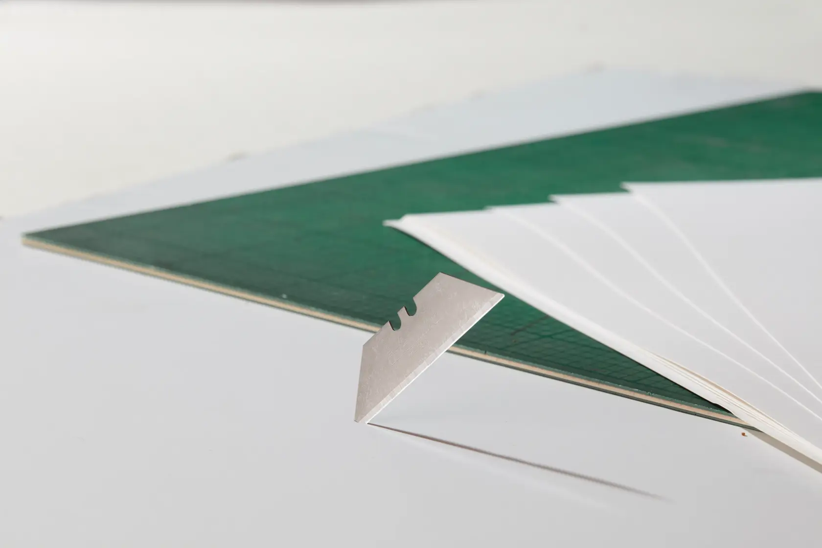 STANLEY 2-11-700 Cutter-Klinge Nahaufnahme neben grünem Schneidematte und weißen Papierblättern.