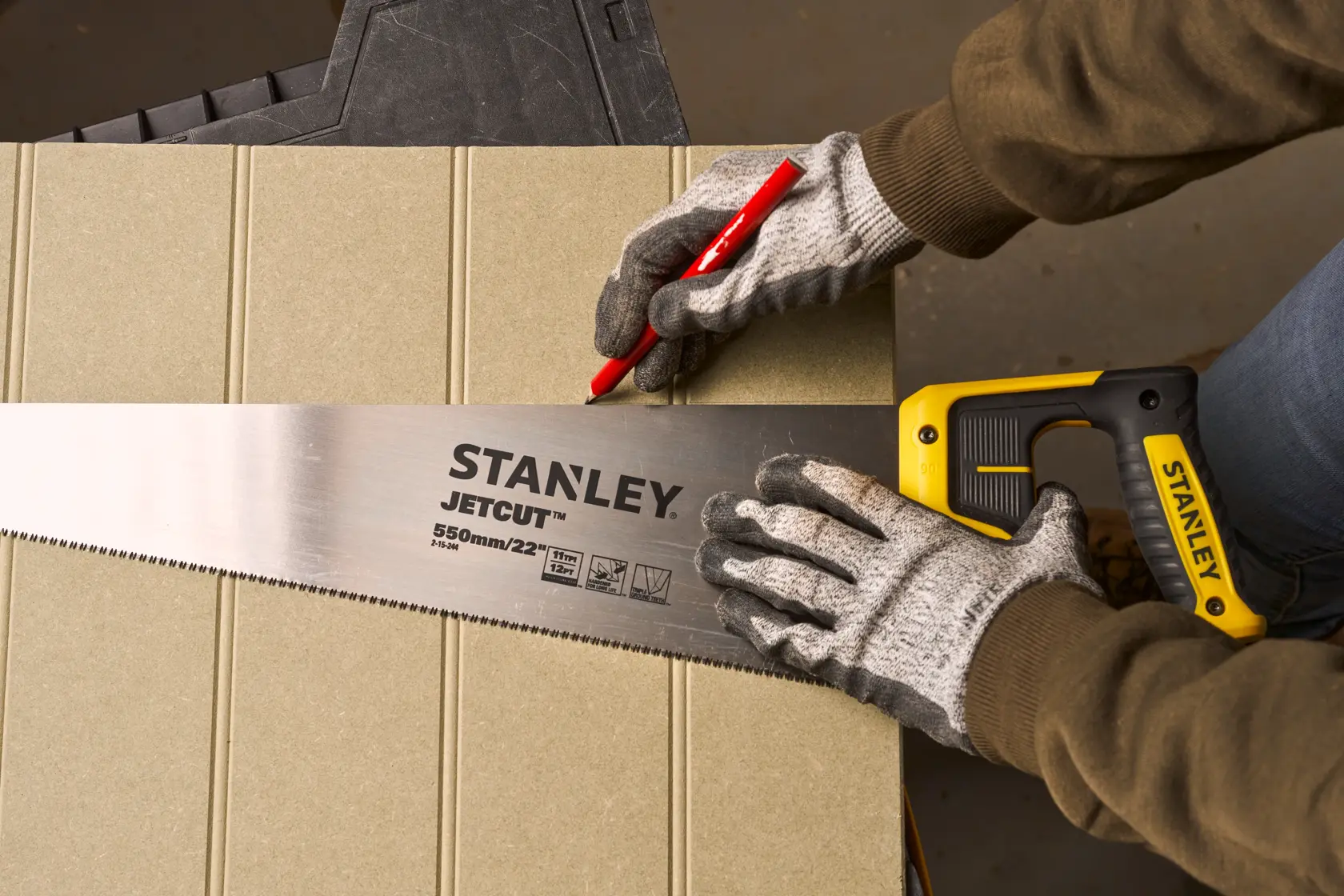 Foto von STANLEY 2-15-244 Handsäge beim Schneiden von Holz auf Sägebock an einer Baustelle.