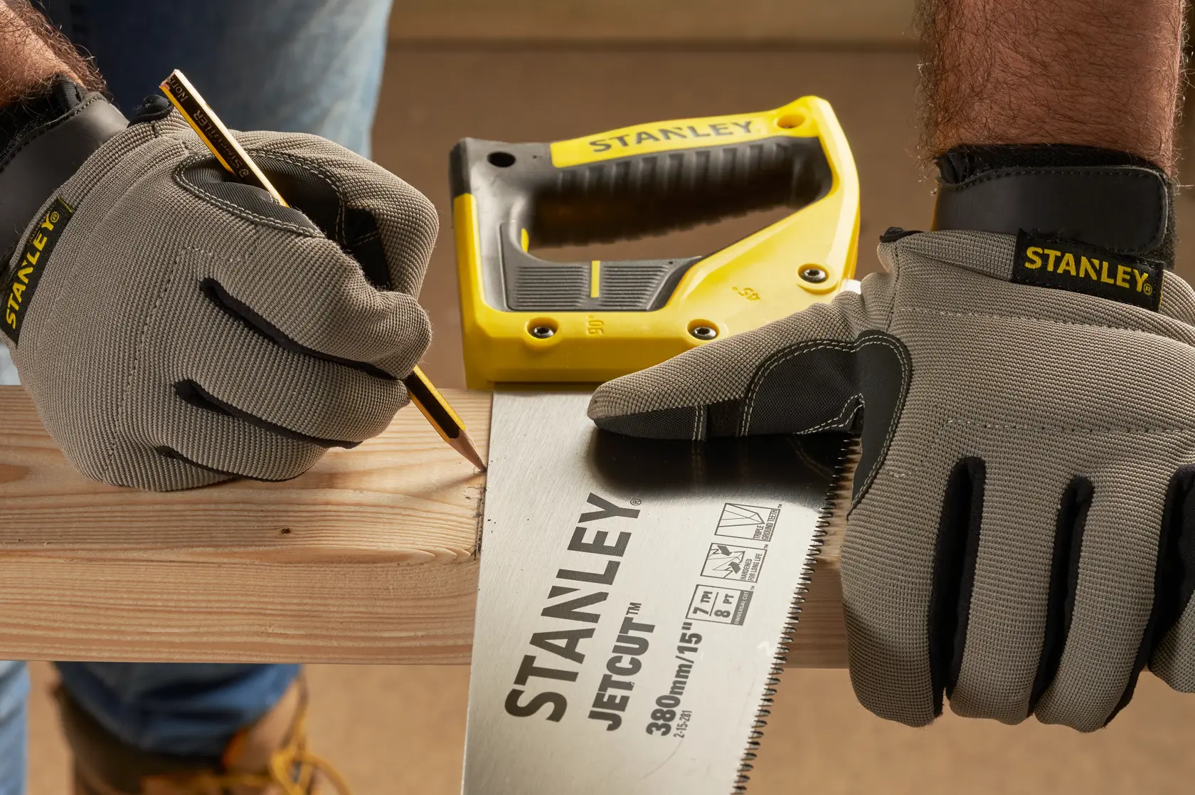 Fotografie STANLEY 2-15-281 Handsäge auf Holz, Arbeiter mit STANLEY Handschuhen markiert Schnittlinie.