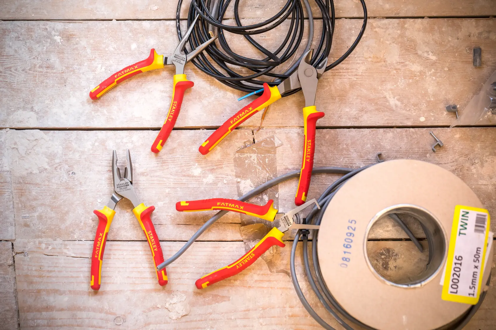 STANLEY 4-84-489 insulated pliers with red and yellow handles on a wooden surface with electrical cables.