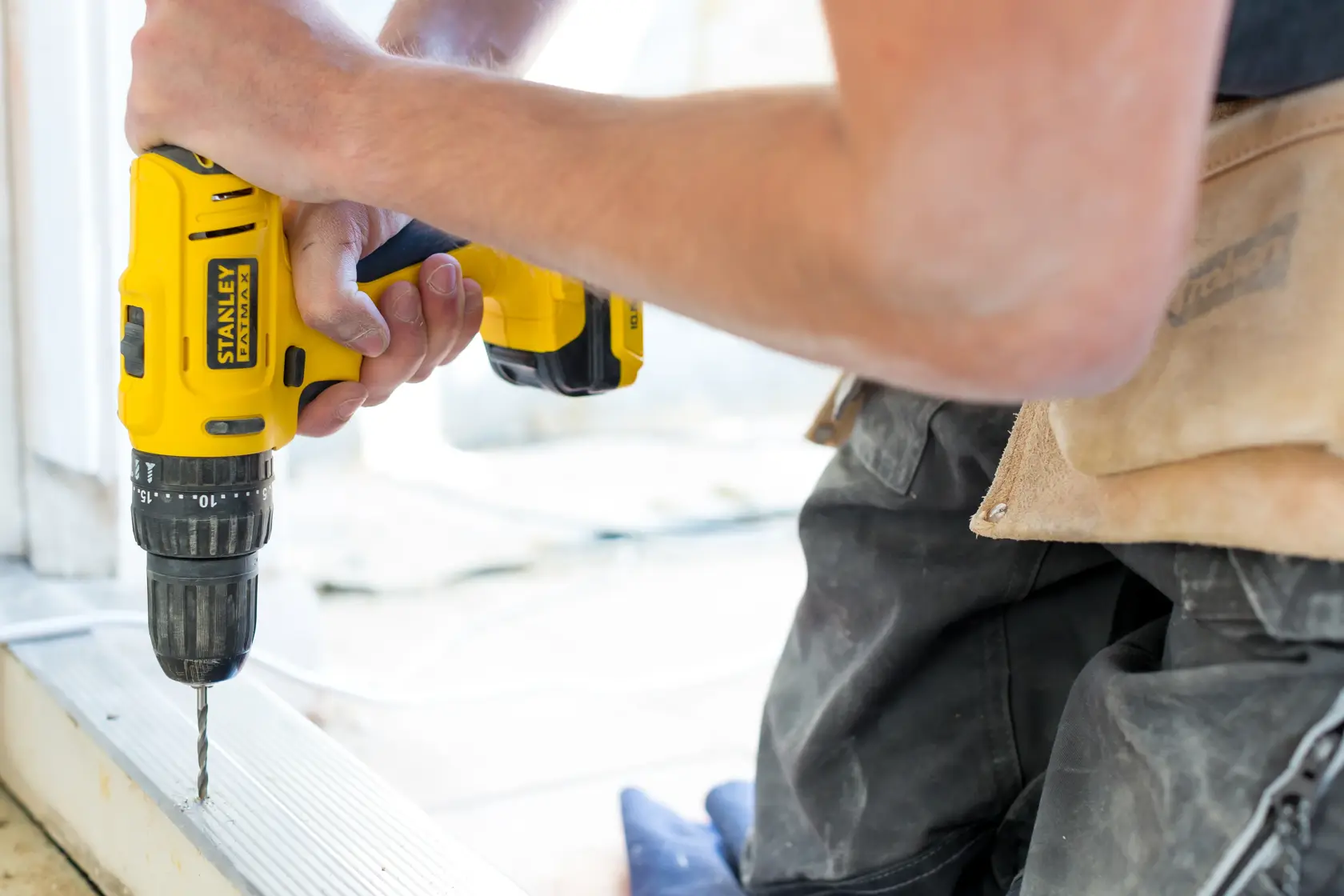 Photo of STANLEY FMC011S2 cordless drill in use, yellow body, close-up side angle.