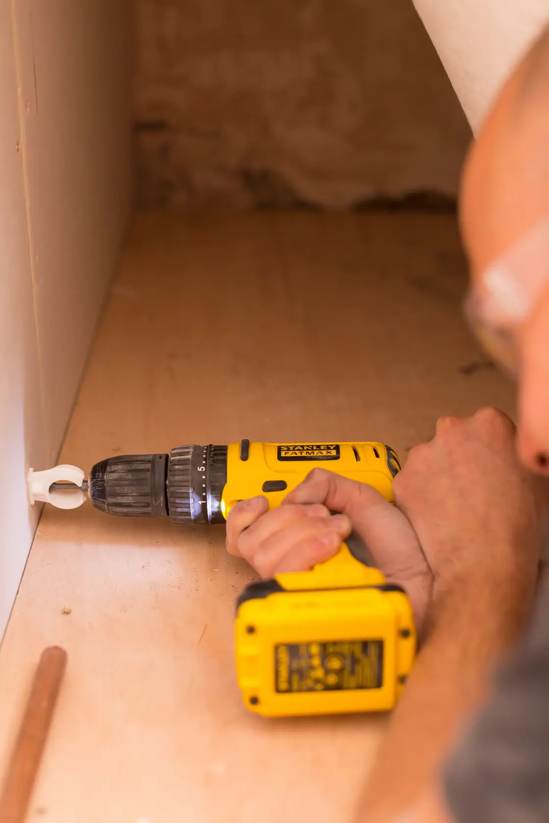 STANLEY FMC011S2 cordless drill in use on wood surface, close-up side angle, photography product category.