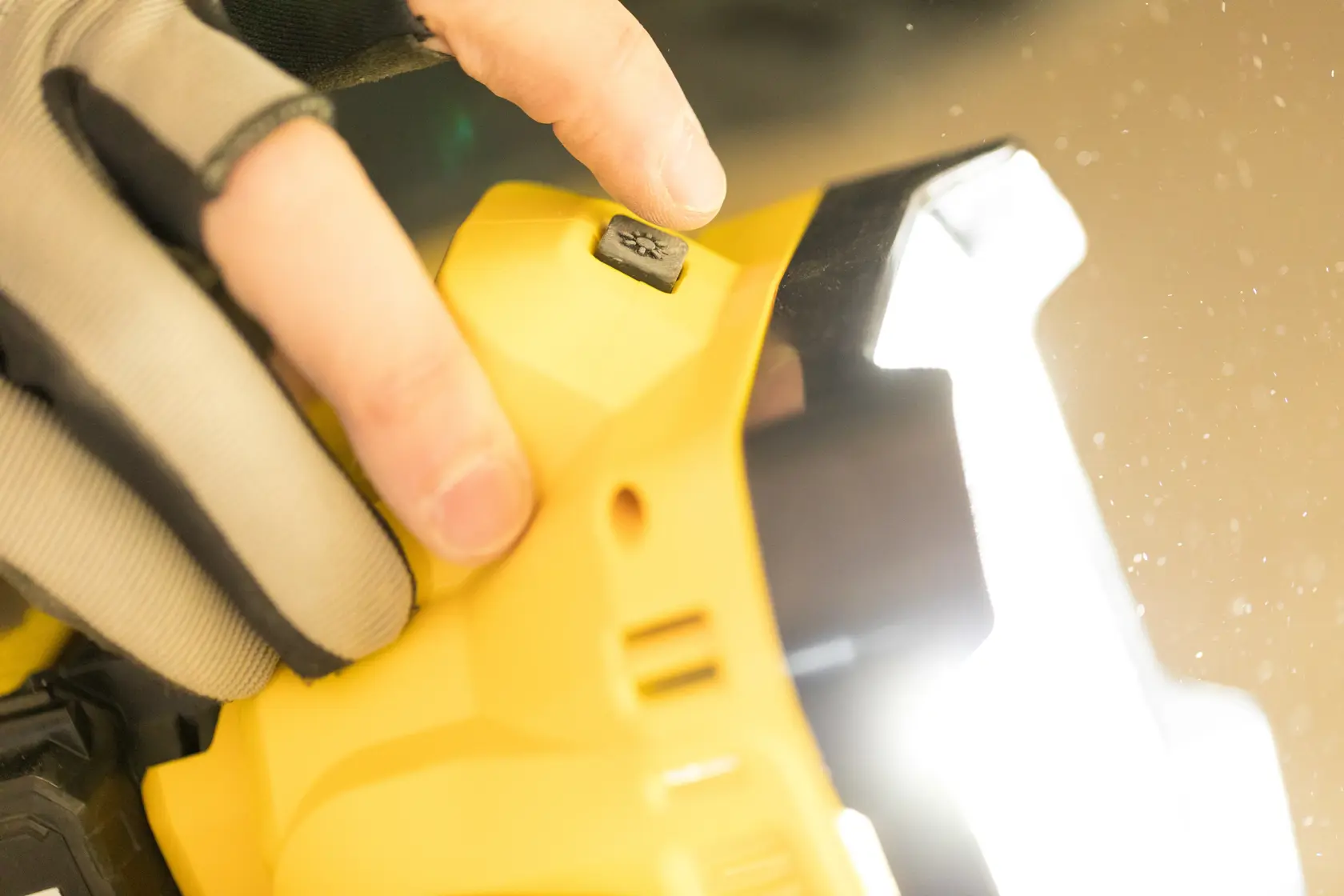 STANLEY FMCL001B Arbeitsleuchte Nahaufnahme, Knopfdetail, Person mit Handschuh, Foto des Produkts im Einsatz.