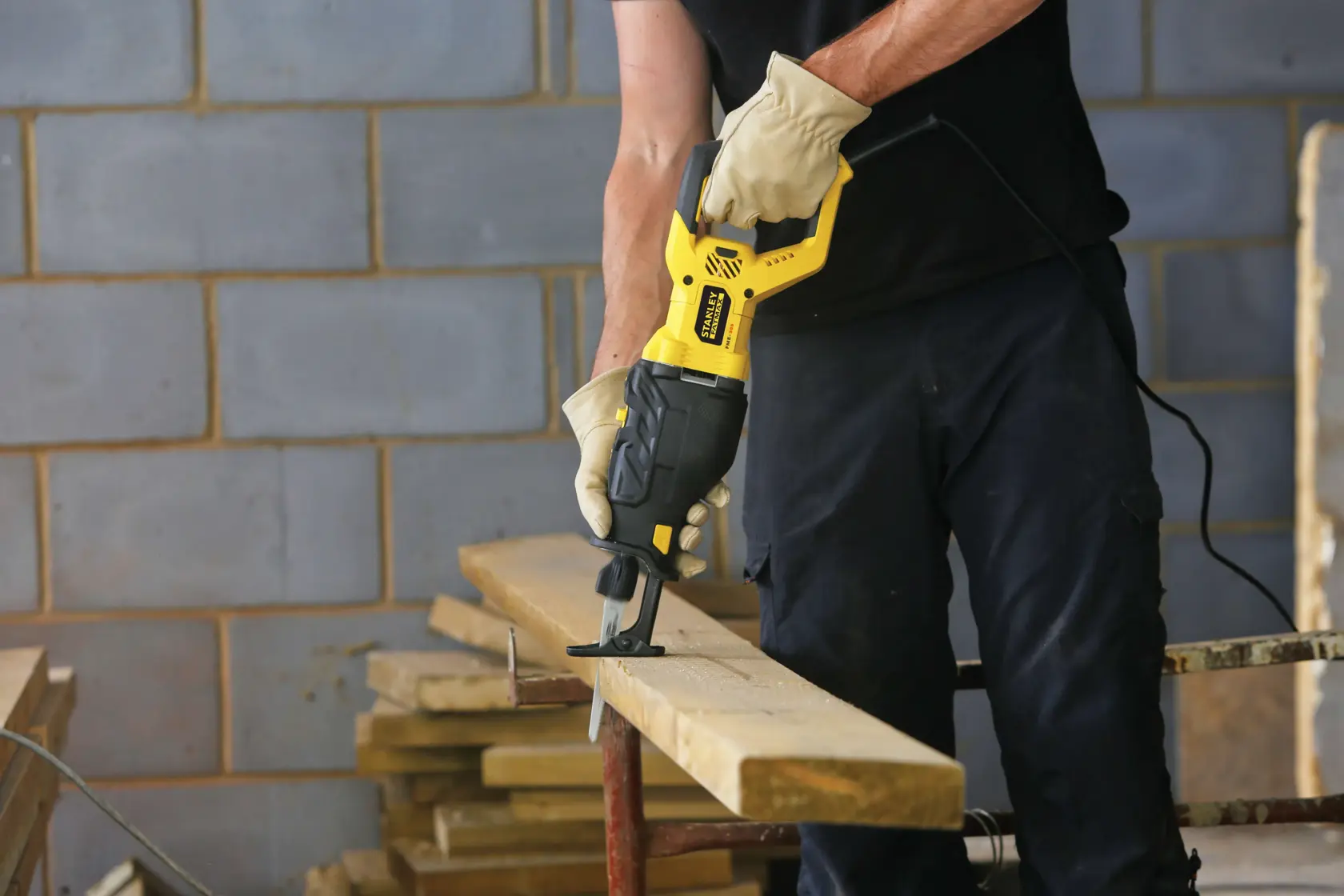 STANLEY FME365K Säbelsäge im Einsatz zum Schneiden eines Holzbretts, Baustellenumgebung, Produktvorführung.
