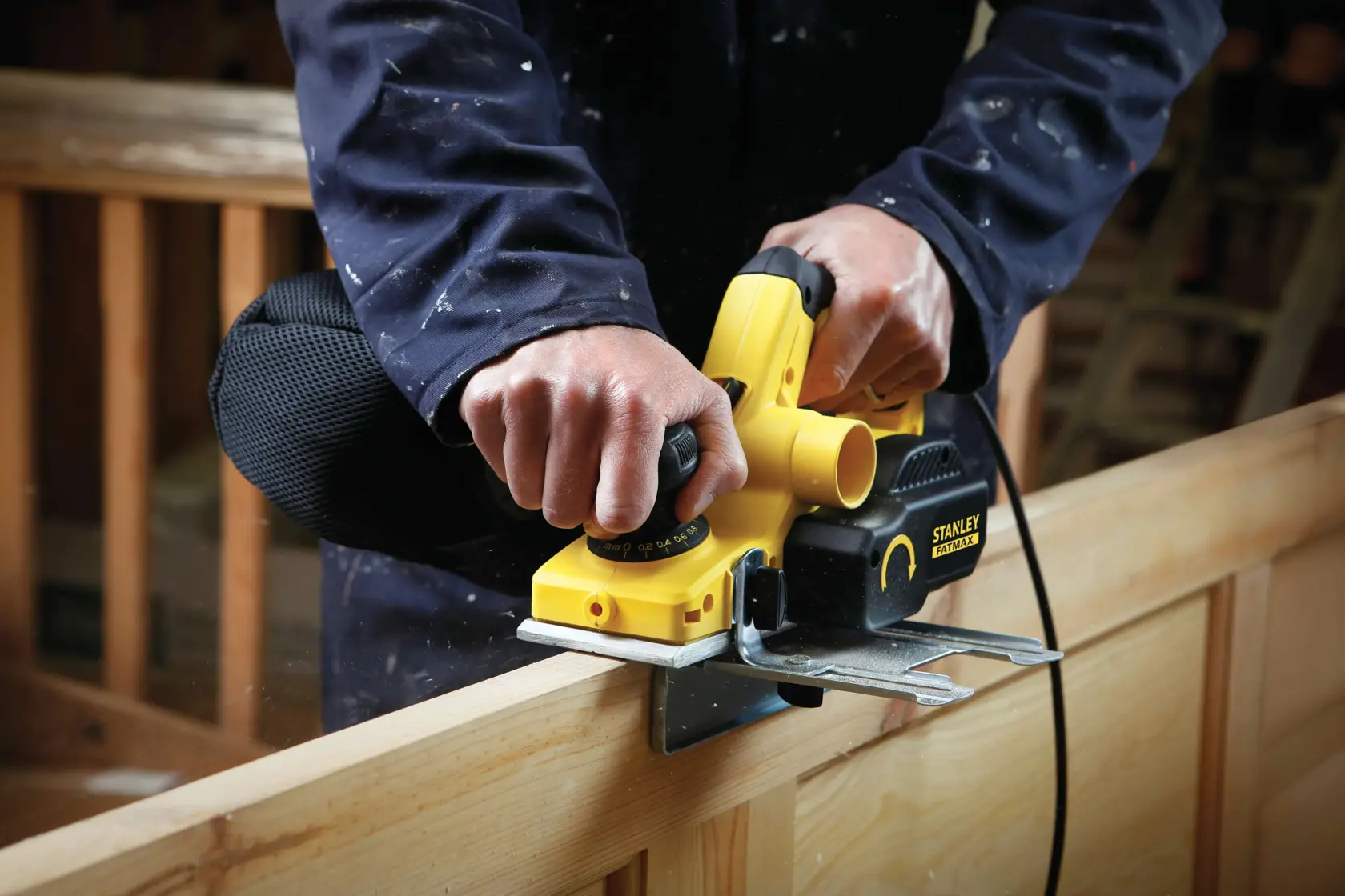 Foto des STANLEY FME630 Hobels beim Glätten von Holz, Nahaufnahme des Werkzeugs in Benutzung durch eine Person in der Werkstatt.