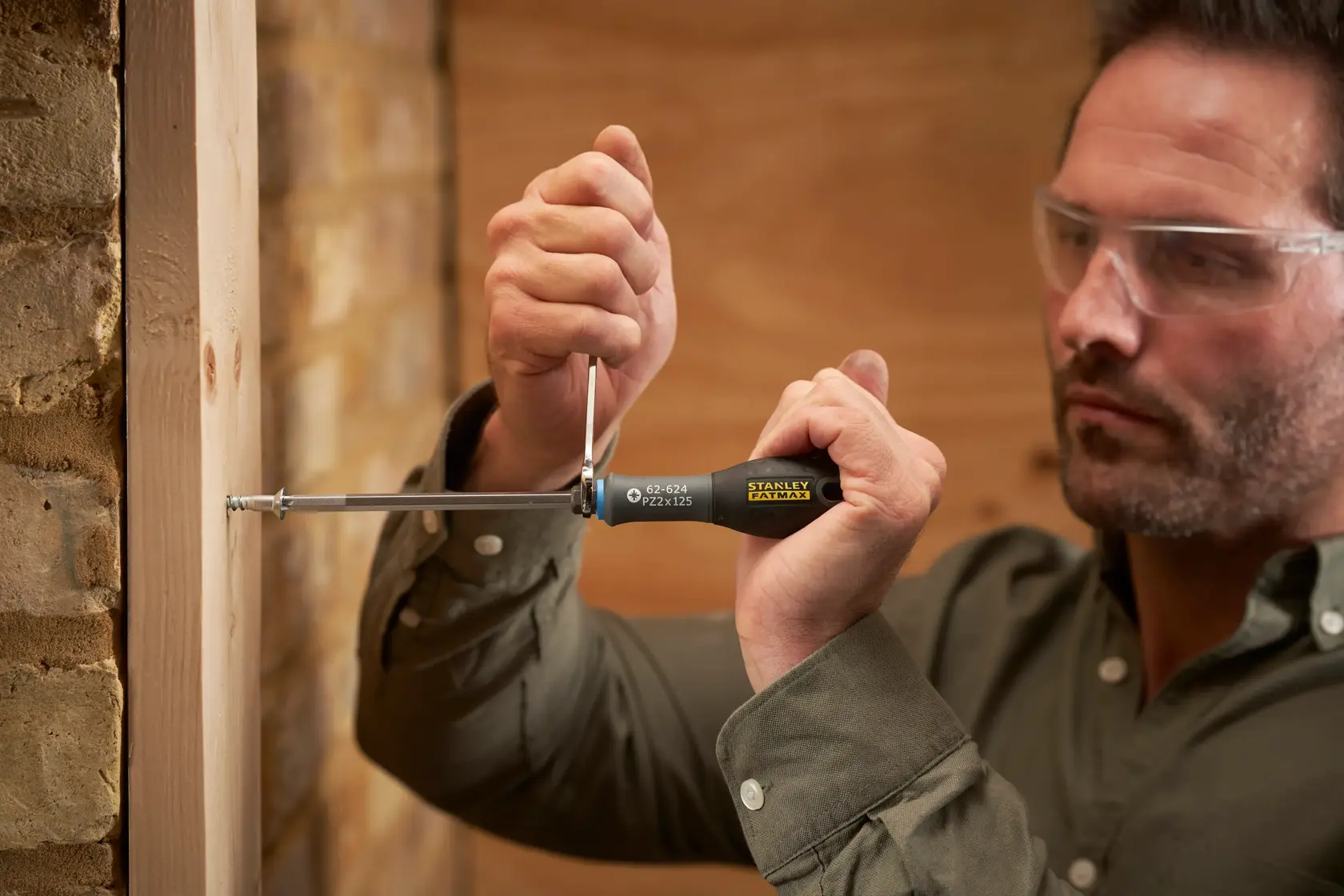 Photo of STANLEY FMHT0-62624 screwdriver being used to drive a screw into wood, close-up of hands and tool.