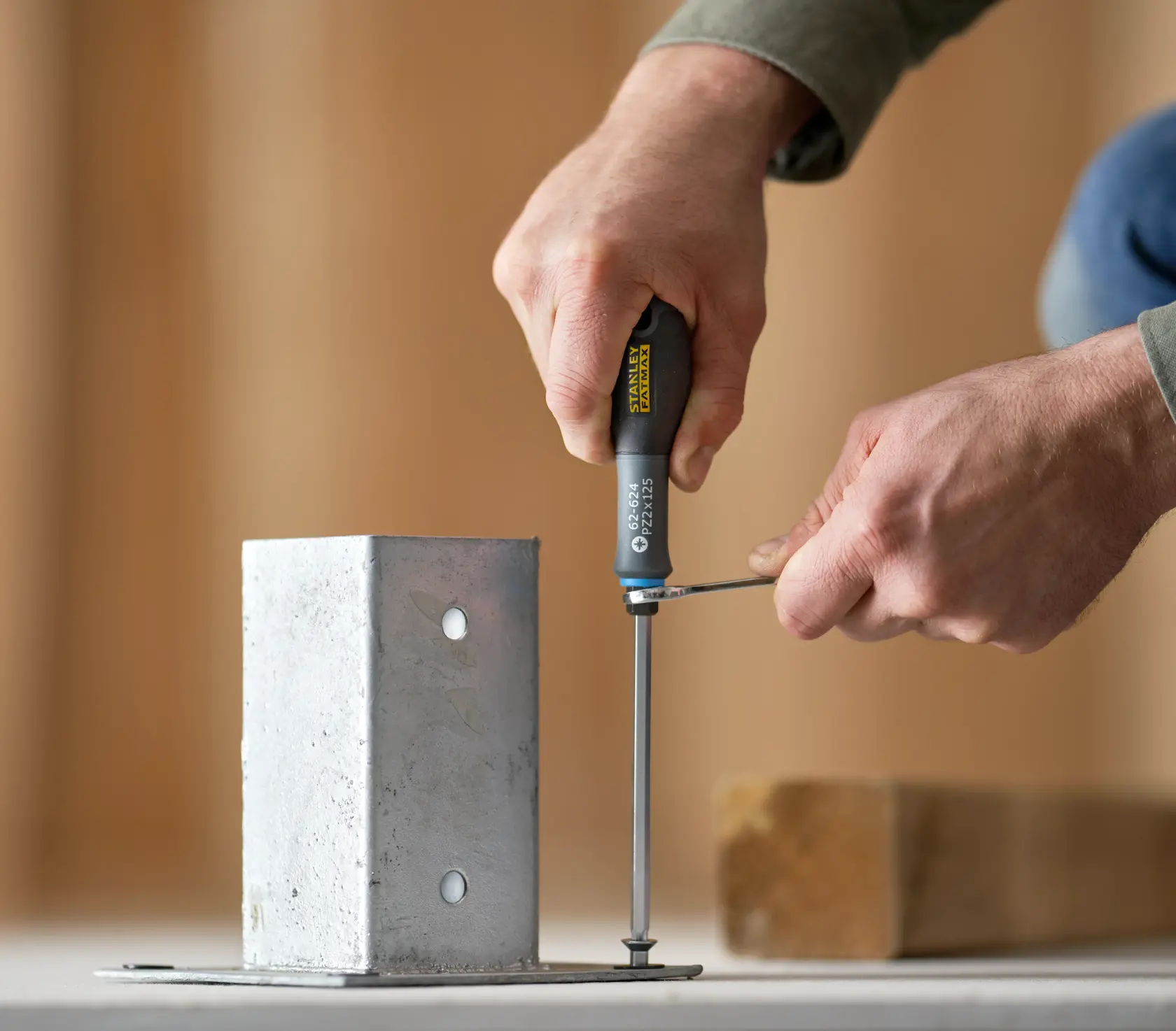 Photo of STANLEY FMHT0-62624 screwdriver being used to fasten a screw into a metal bracket on a flat surface.