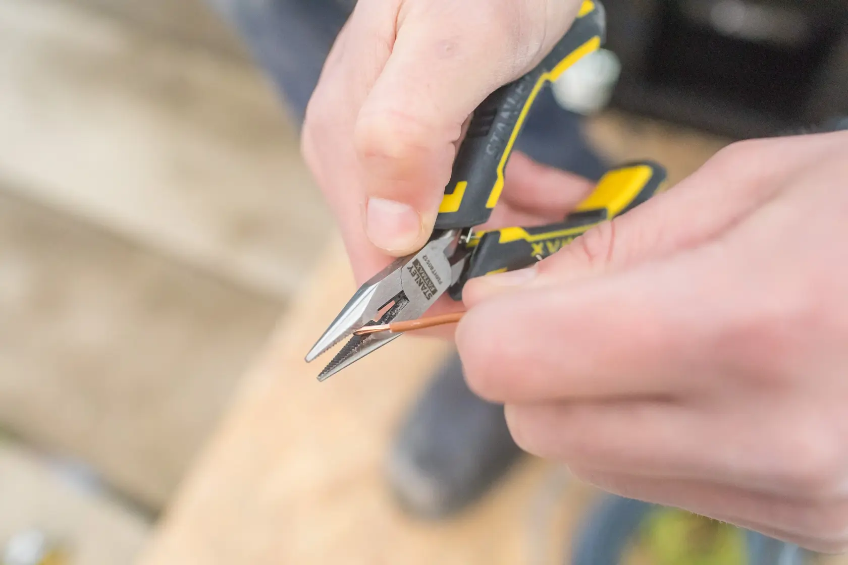 Stanley FMHT0-80517 Zange mit gelbem und schwarzem Griff schneidet Kupferdraht, Nahaufnahme.