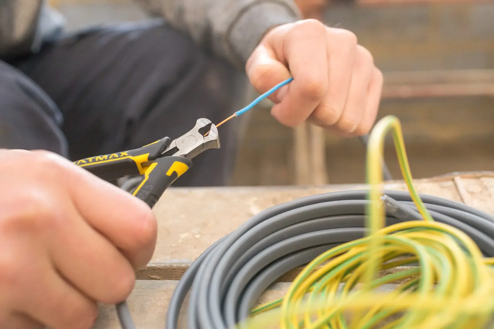 Stanley FMHT0-80519 diagonal pliers cutting wire, close-up photo during electrical work.