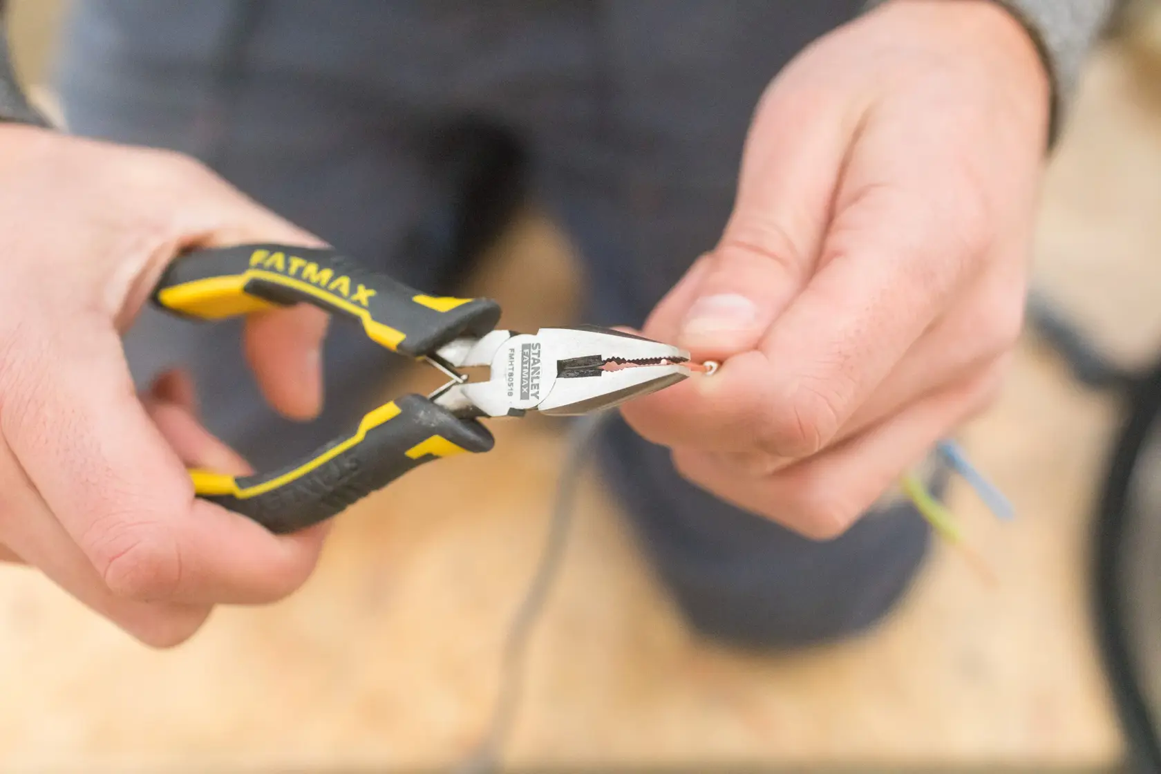 STANLEY FMHT0-80524 Zange mit gelb-schwarzem Griff hält Draht, Nahaufnahme in der Hand.
