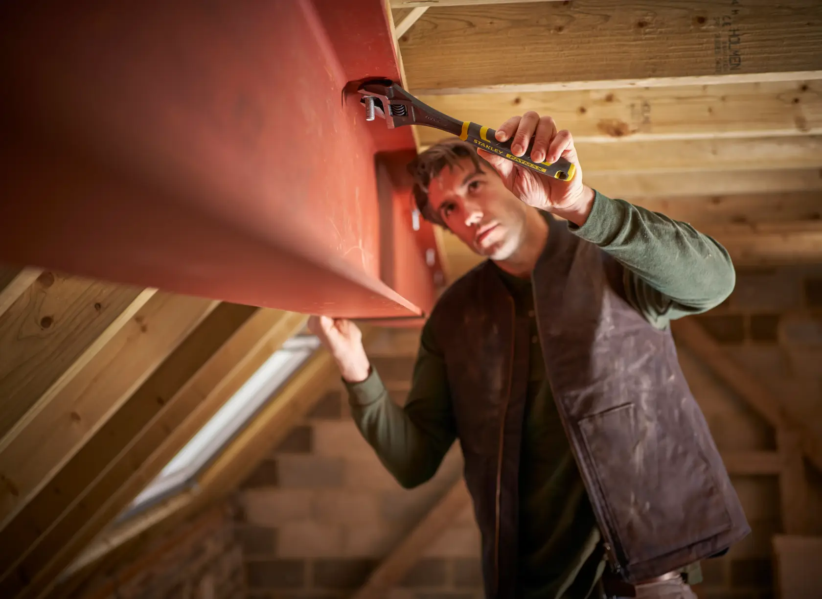STANLEY FMHT13125-0 adjustable wrench used on red steel beam in attic construction, close-up photography.