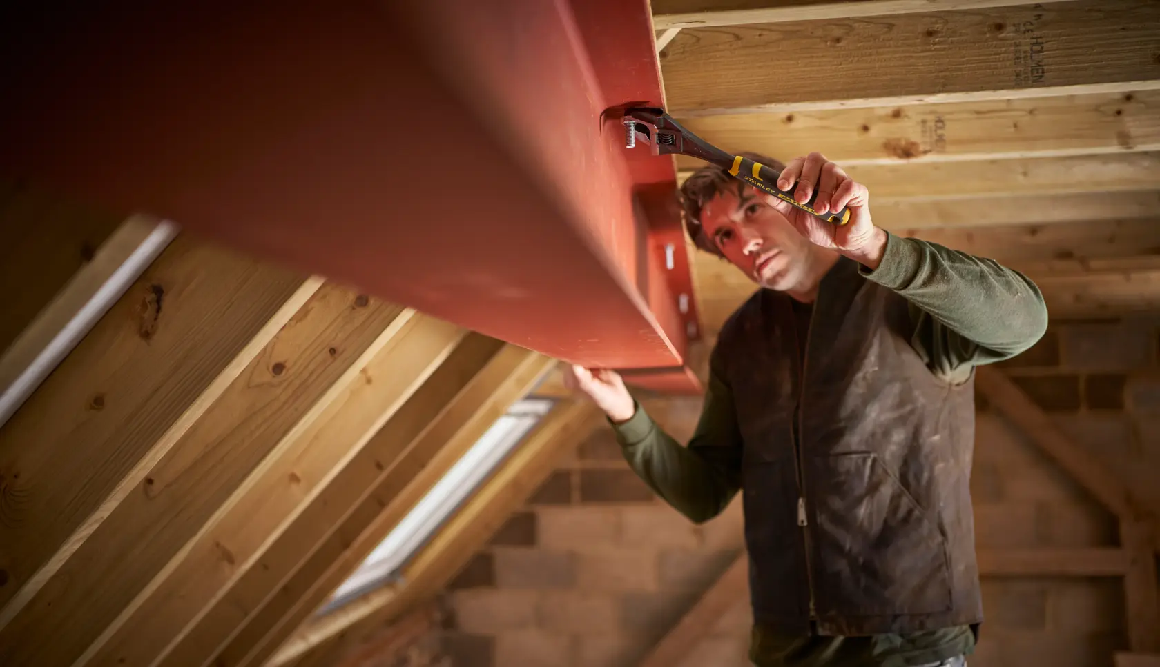STANLEY FMHT13126-0 adjustable wrench in use tightening bolt on steel beam in attic construction.