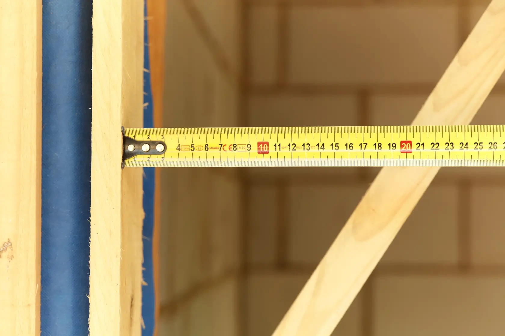 Foto des gelben STANLEY FMHT36142-0 Maßbands, über Holzbalken gespannt, Nahaufnahme.