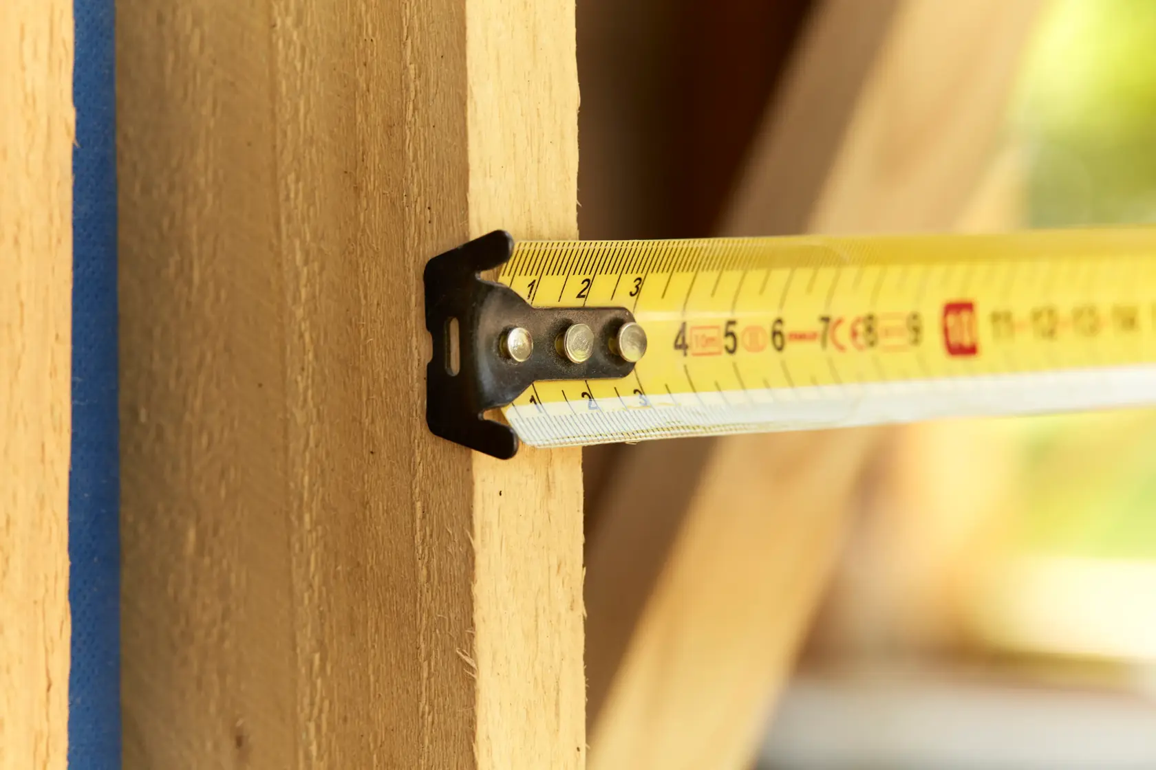 STANLEY FMHT36142-0 Maßband auf Holzträger ausgerollt, Nahaufnahme, gelbe metrische Markierungen.