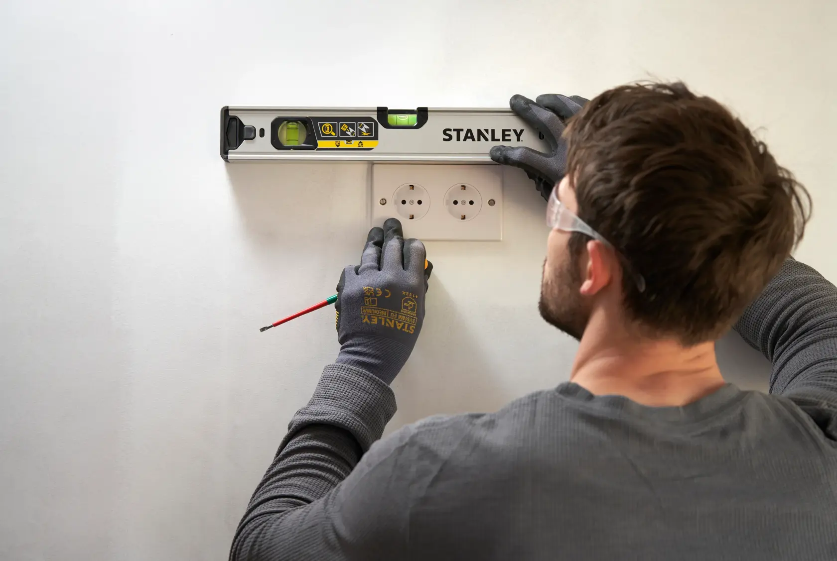 STANLEY FMHT43670-1 Wasserwaage im Einsatz, Person markiert Wand über Steckdosen, Ansicht von oben.