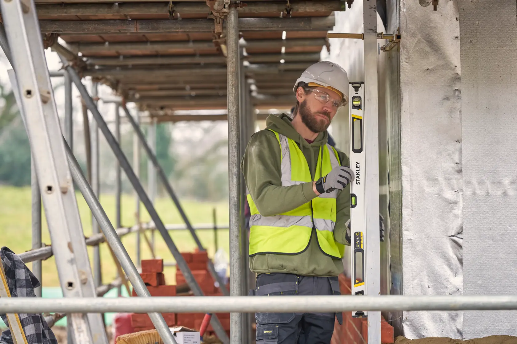 STANLEY FMHT43675-1 Wasserwaage wird vertikal auf einer Baustelle von einem Arbeiter mit Sicherheitsweste verwendet.