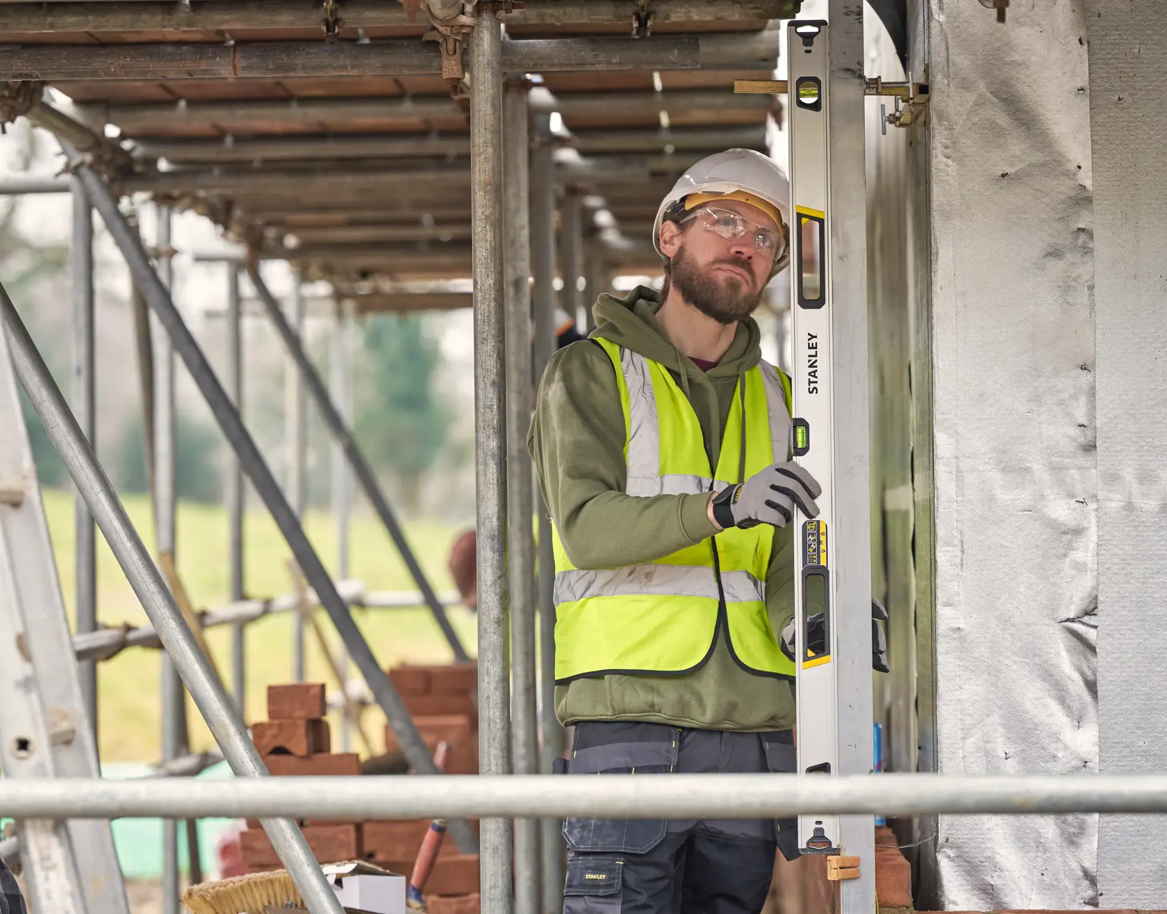 STANLEY FMHT43677 Wasserwaage, verwendet von einem Arbeiter mit Warnweste auf einer Baustelle.