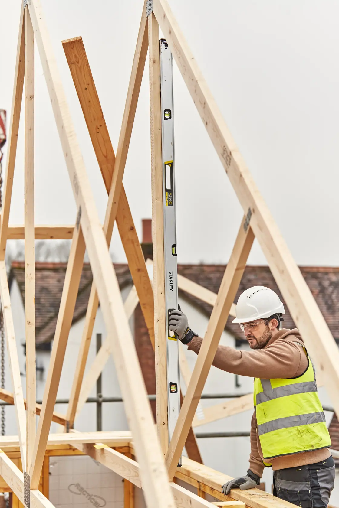 STANLEY FMHT43680-1 Wasserwaage senkrecht gehalten von Arbeiter an Baustelle mit Holzbalken.
