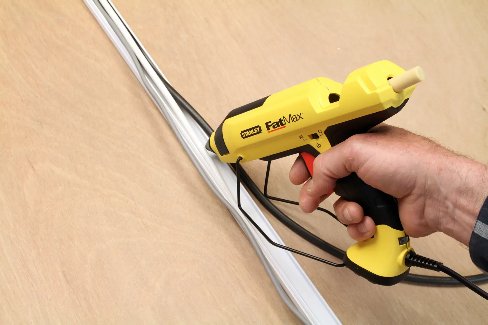 STANLEY FMHT6-70418 pistola per colla FastMax gialla usata per installare cavi su una parete.