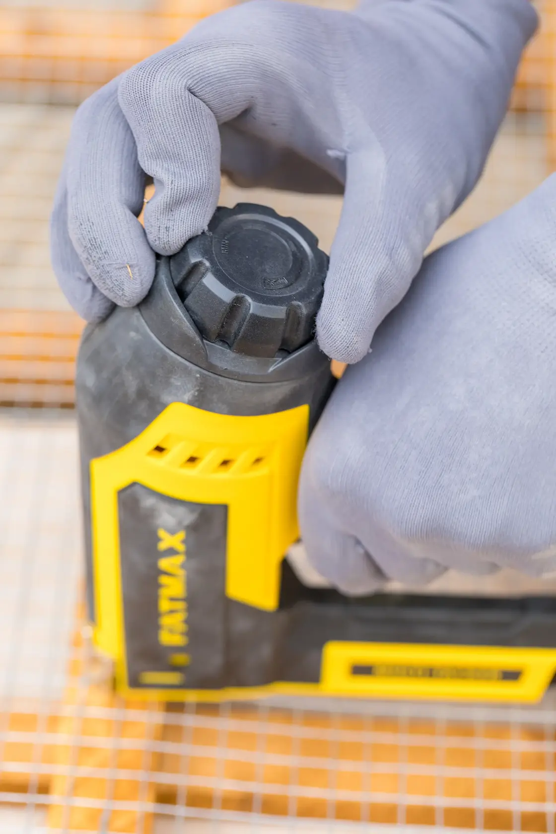 STANLEY FMHT6-75934 Nahaufnahme einer Person, die ein gelb-schwarzes Handwerkzeug mit Handschuhen einstellt.