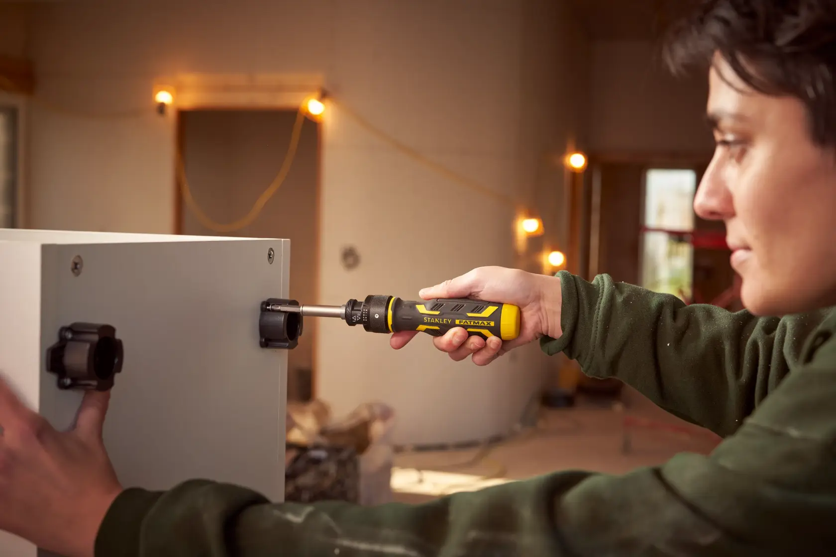 Stanley FMHT62692-0 ratcheting screwdriver used to install hardware on cabinet in workshop setting.